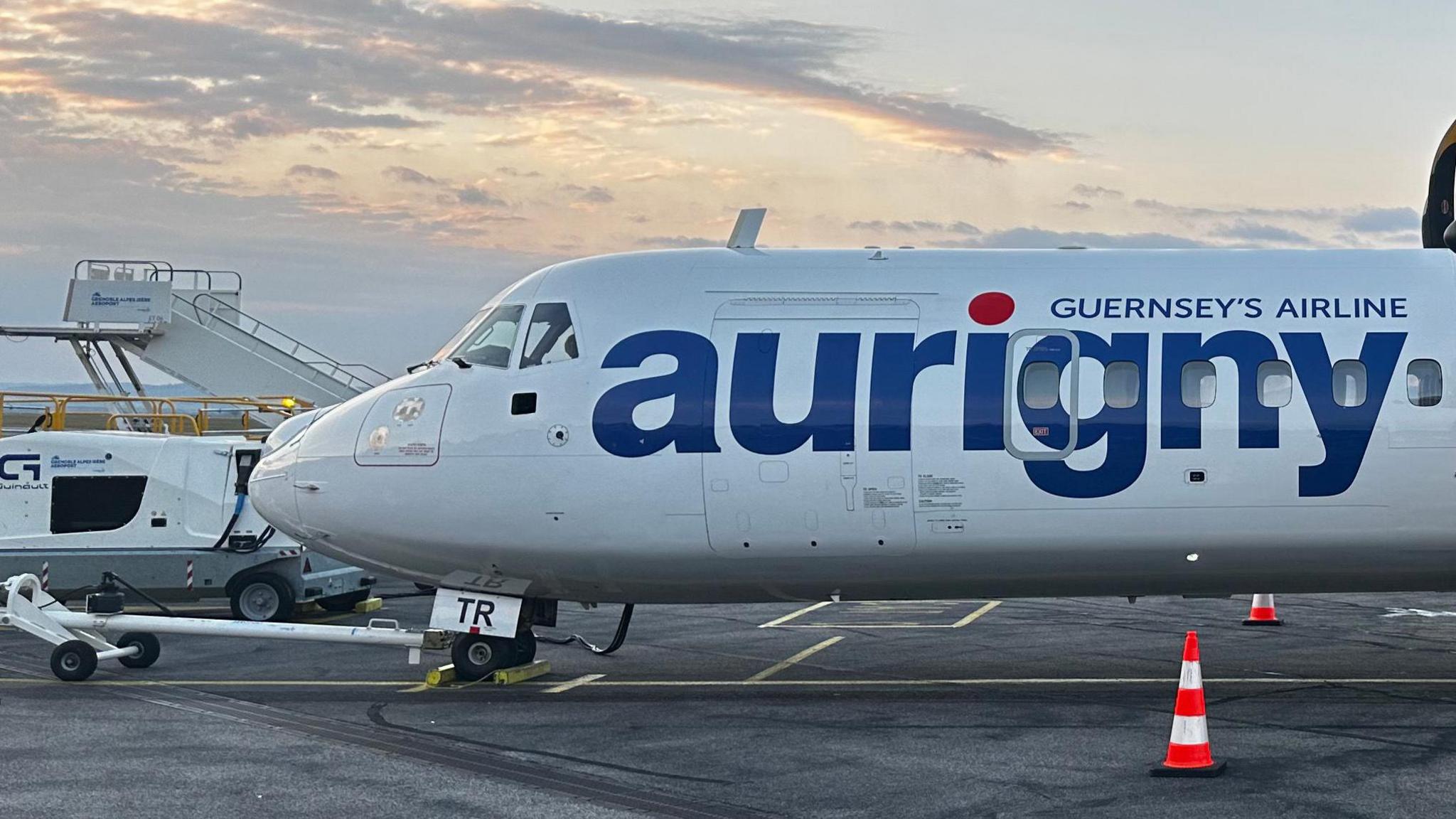 A white Aurigny aircraft with the company's name on the side in bold, blue writing.