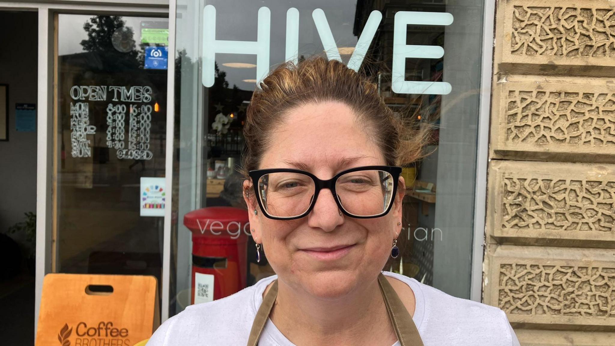 Gabby Hurts, owner of Hive Cafe, smiling in front of her cafe window.