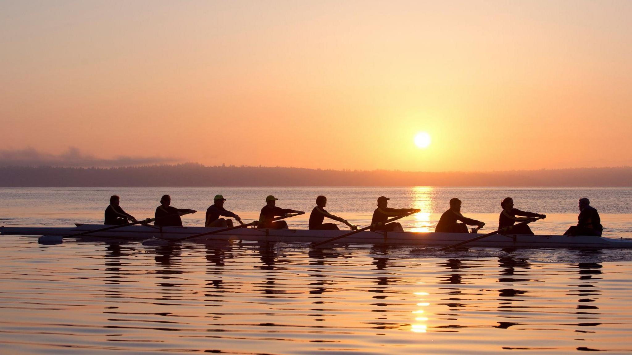 9 people row in the sunset.