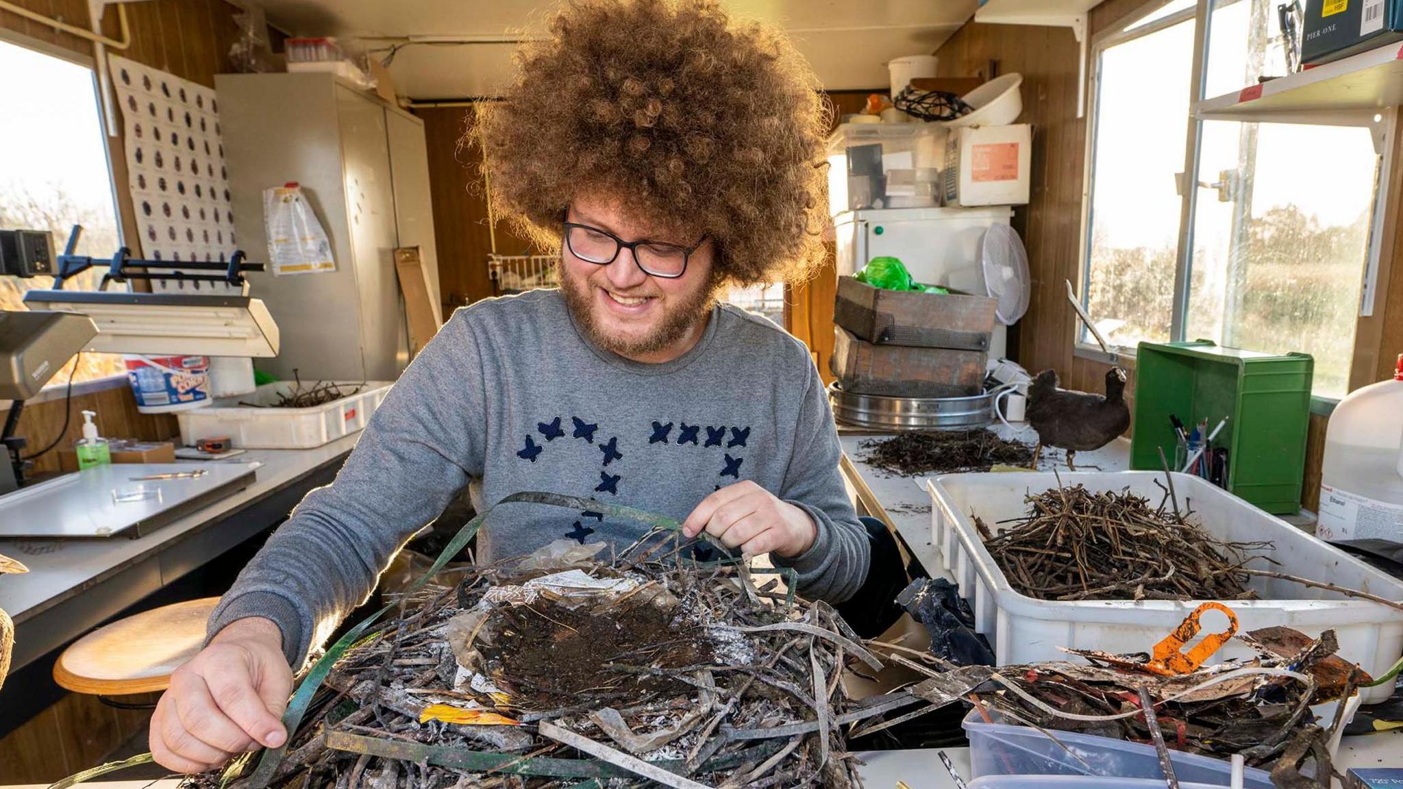 man looks at birds nest on a table 