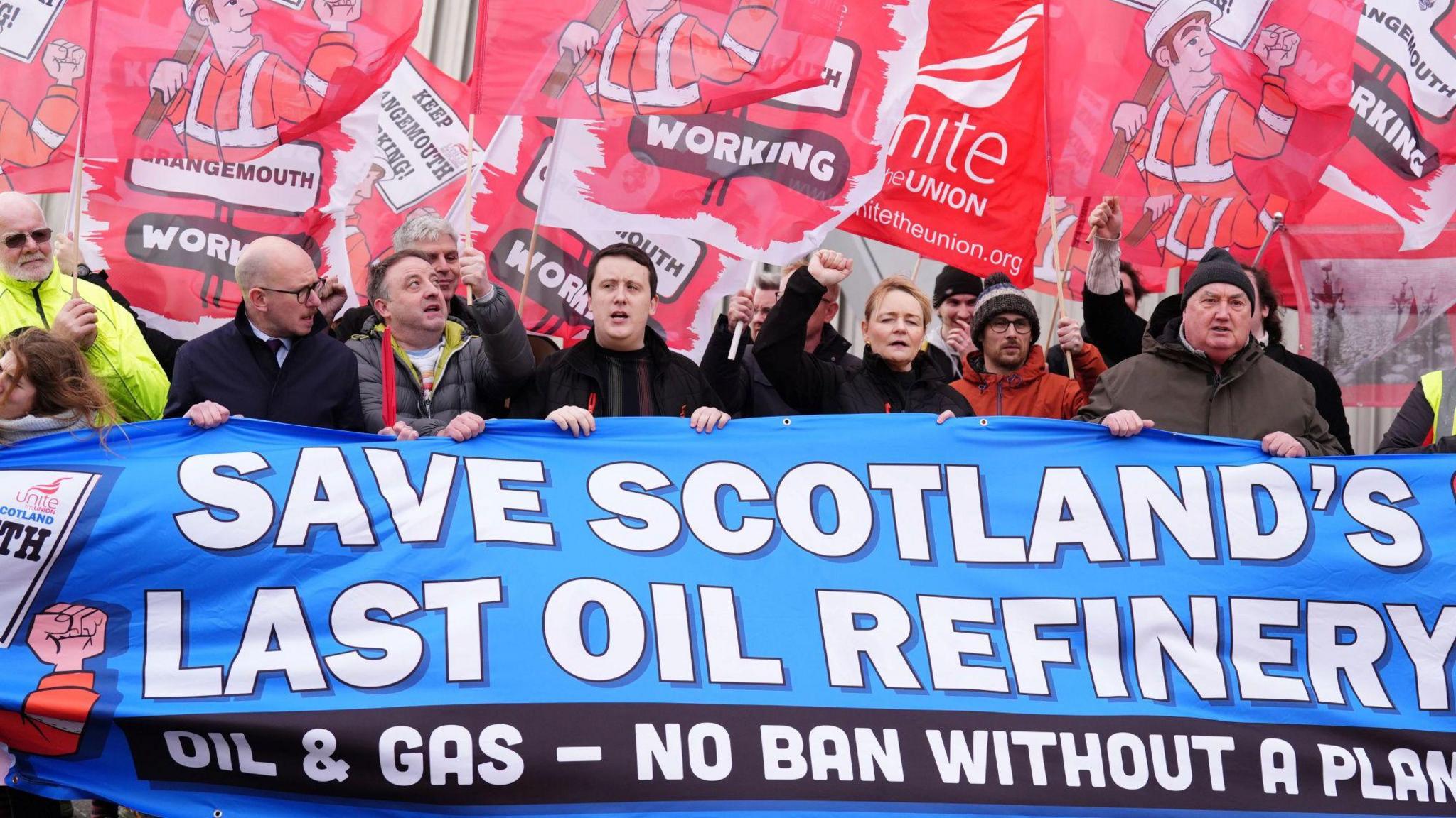 Workers gather behind a banner reading 'Save Scotland's last oil refinery' while holding placards