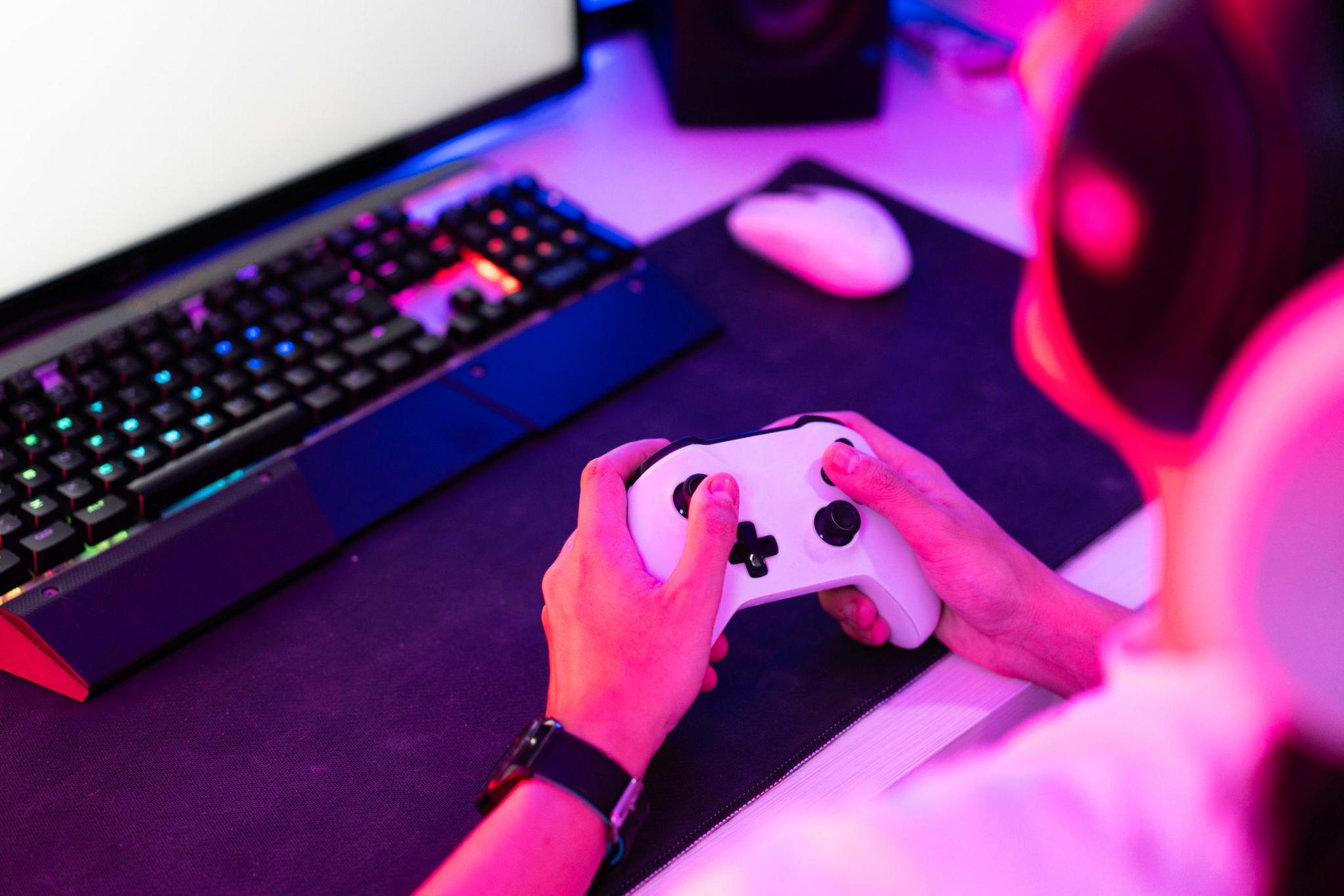 Gamer holding gamepad and playing video game on desktop