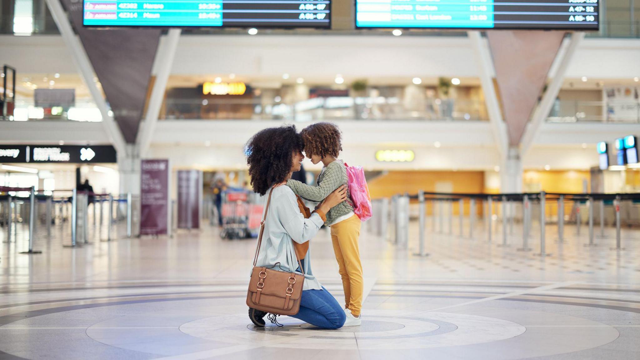 Woman hugging child at airport.