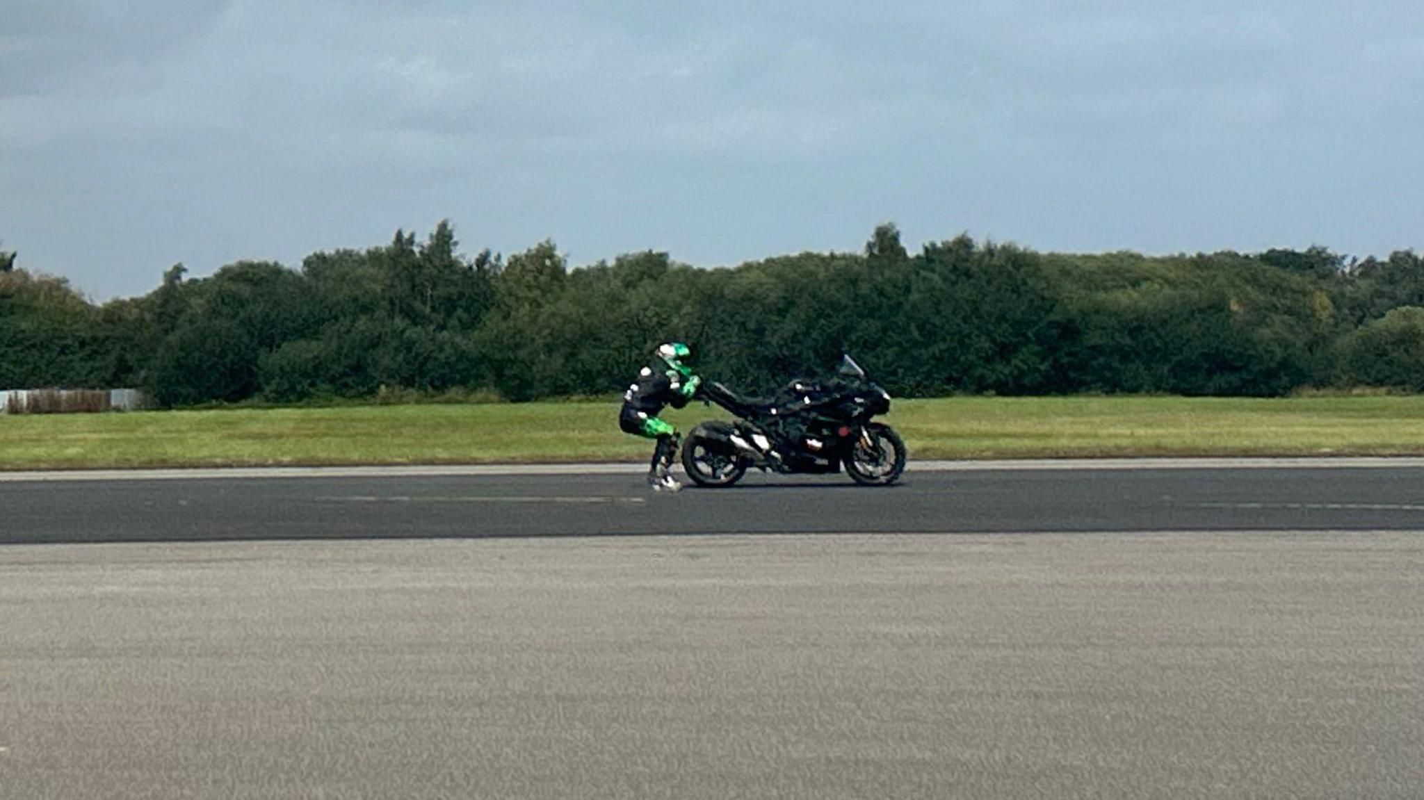 Jonny Davies in a helmet and black motorcycle gear being dragged behind a motorbike at Elvington Airfield