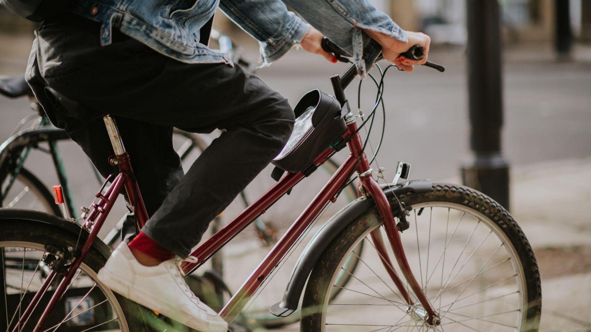 A man cycling a red bike on a road. 