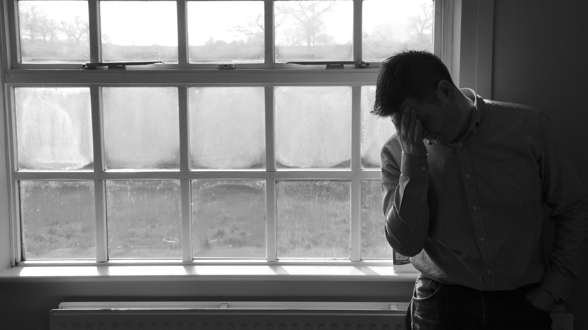 Man by a window with his head in his hand