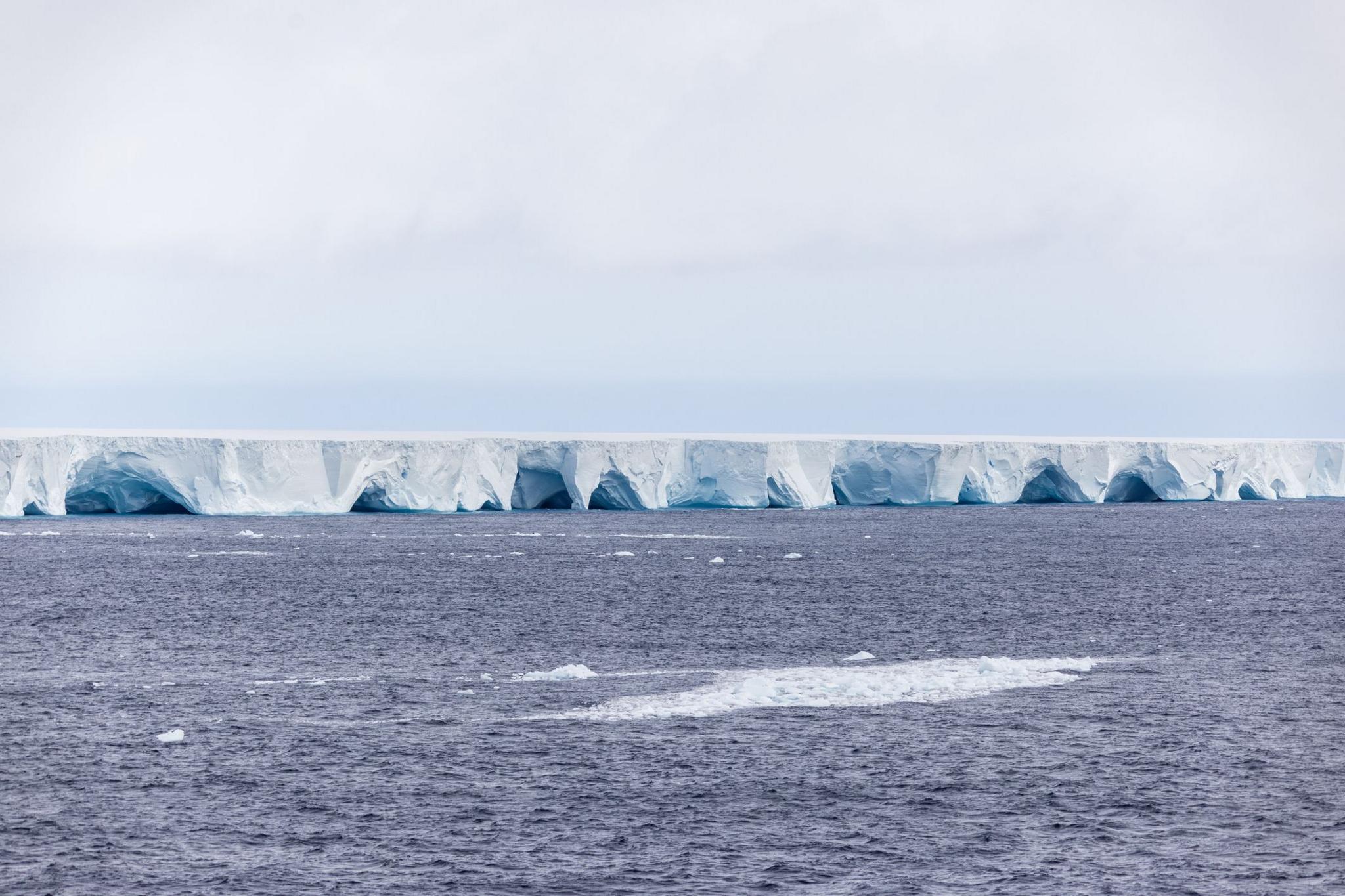 A photograph showing the sides of the iceberg with arches and caves