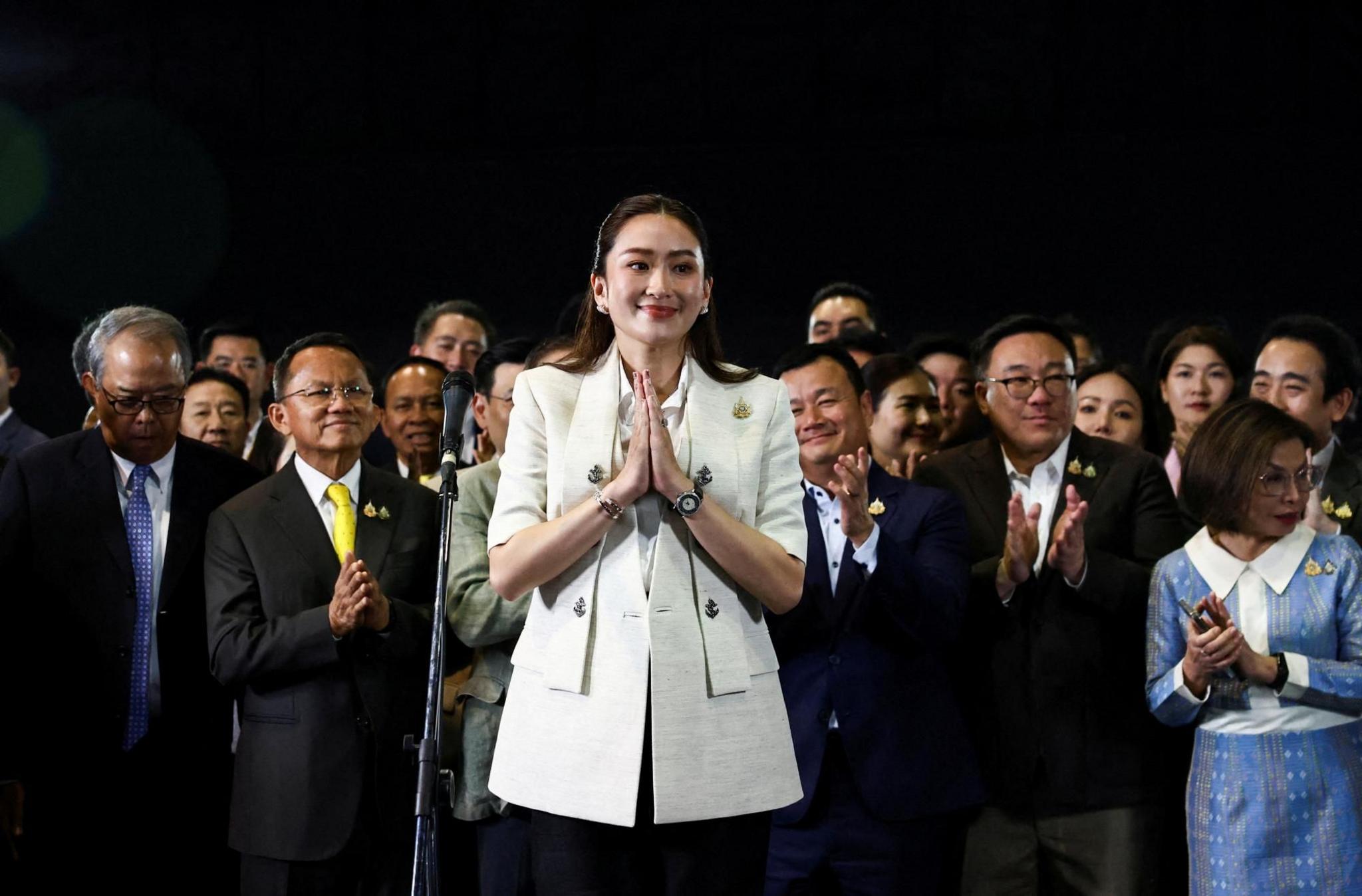 The new Thai PM Paetongtarn Shinawatra smiles as she is surrounded by people during a press conference 