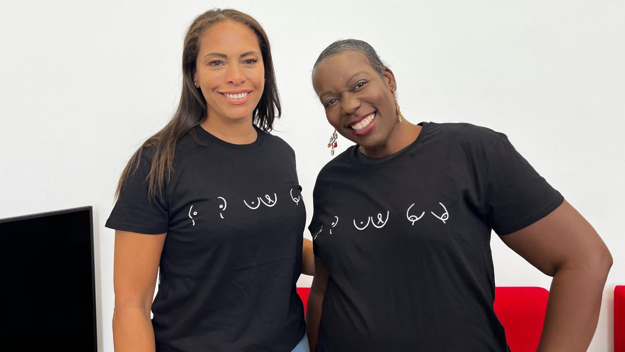 Two women smile wearing matching-shirts for a breast cancer awareness campaign