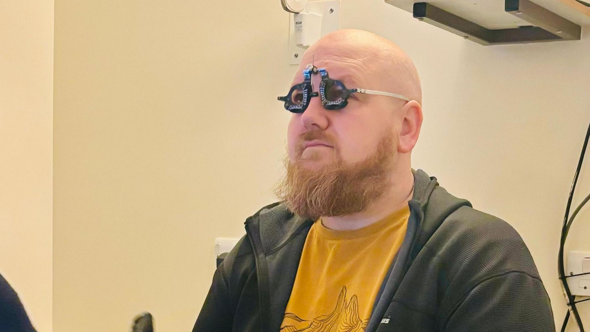 Paul Laskey seated in a clinical room, undergoing eye sight tests. 