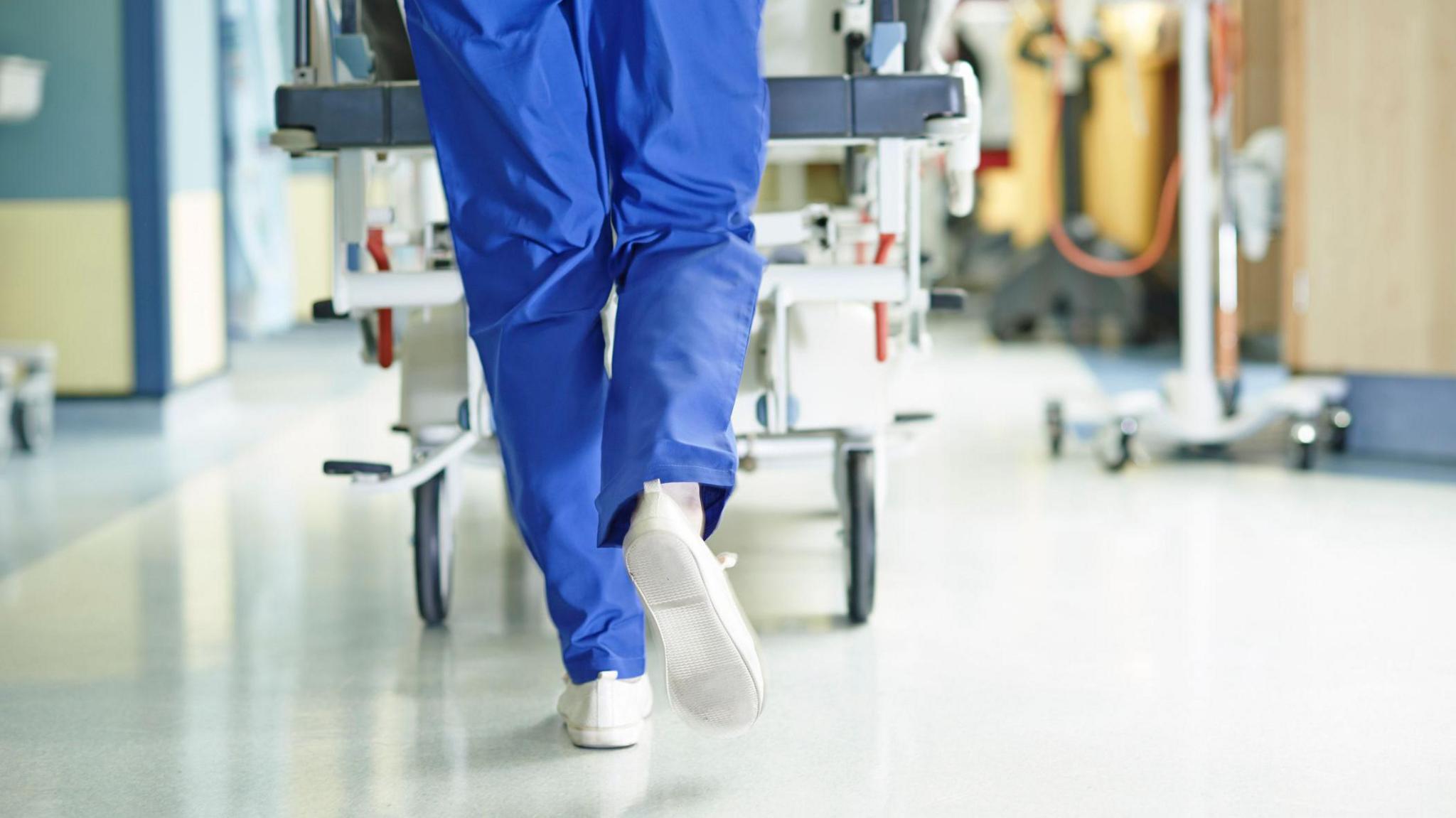 Surgeon walking a hospital bed down a corridor