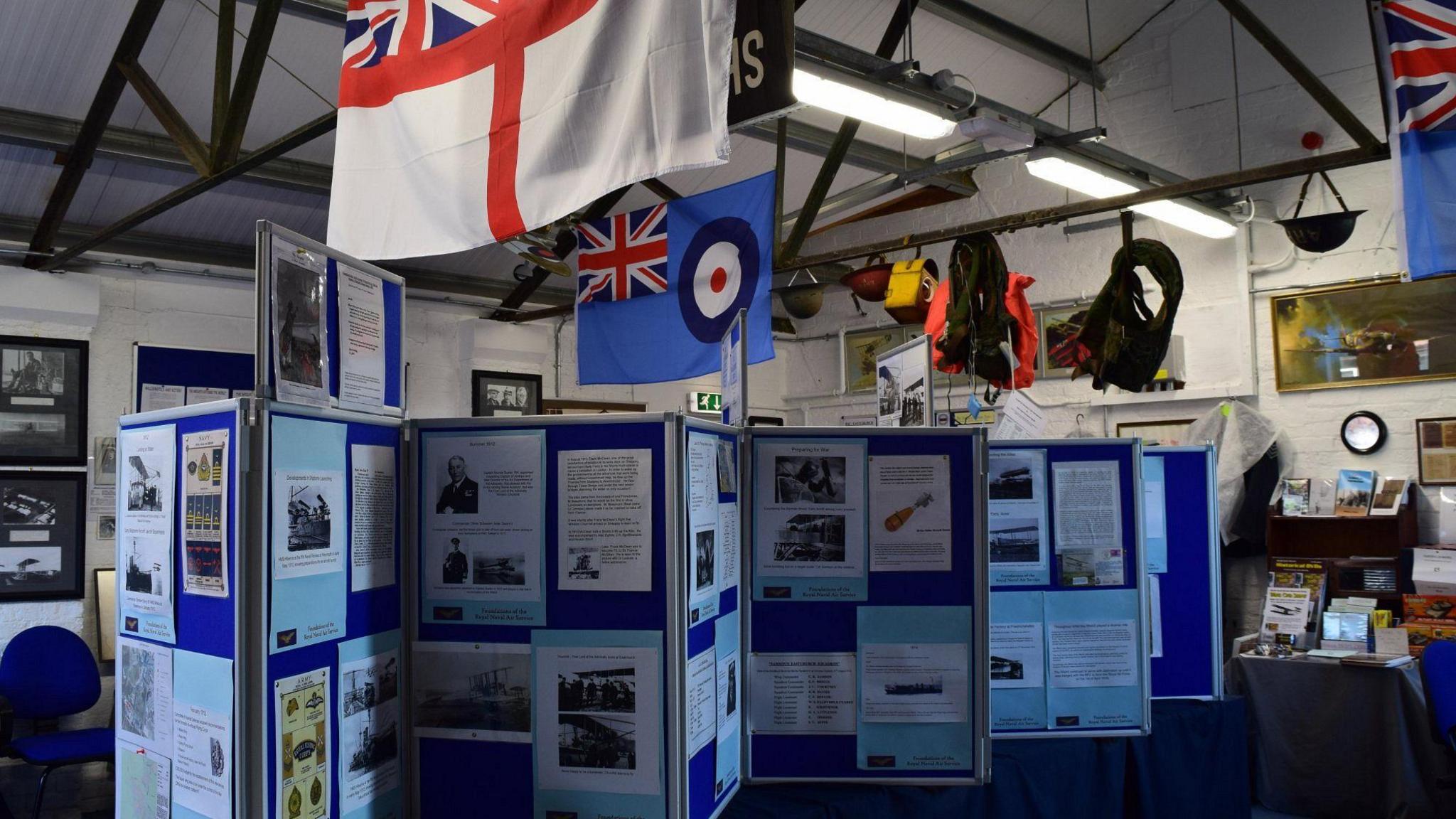 Exhibits in the Eastchurch Aviation Museum, including two flags and display boards.