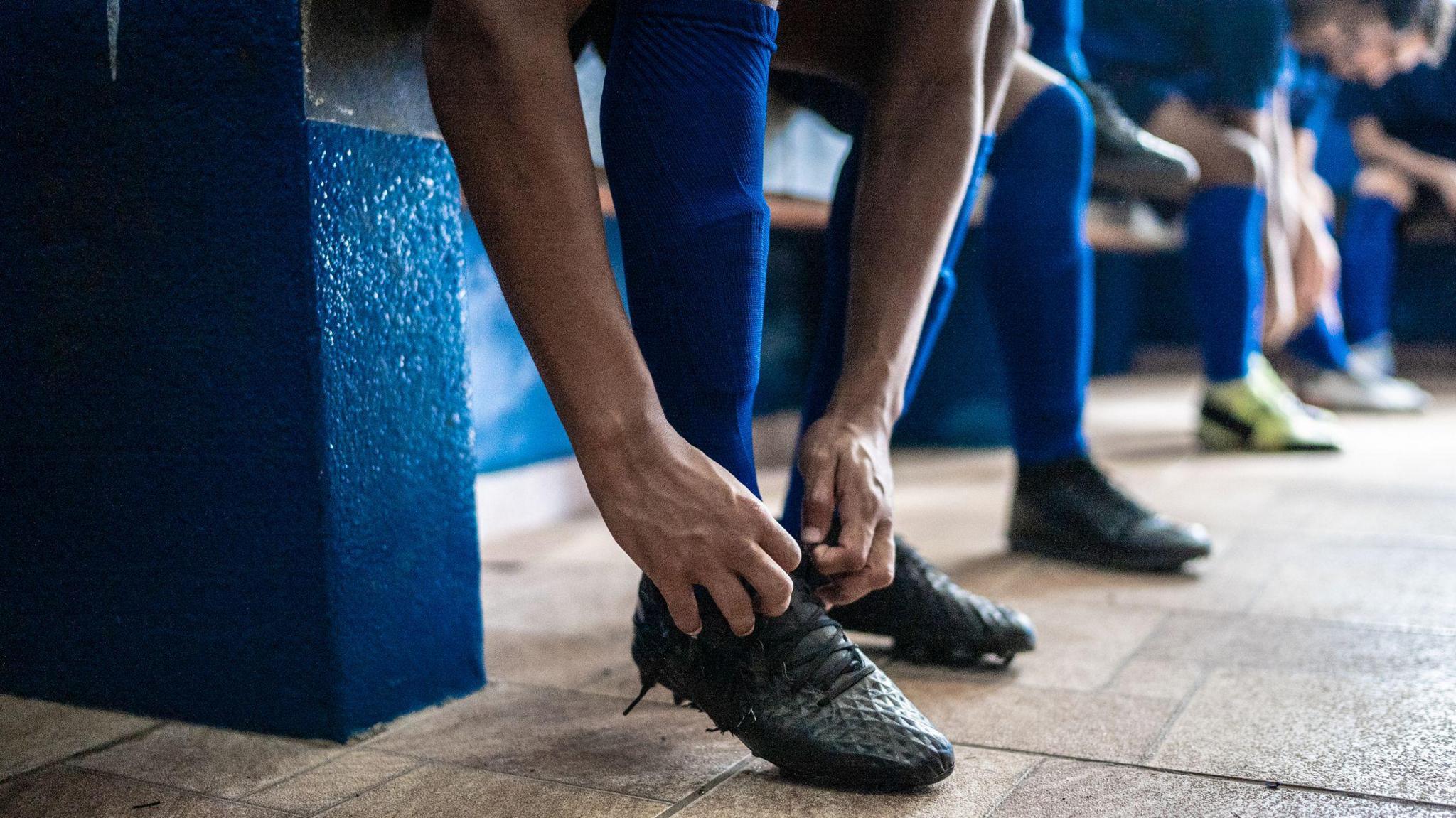 A generic image of people putting on football trainers in a locker room