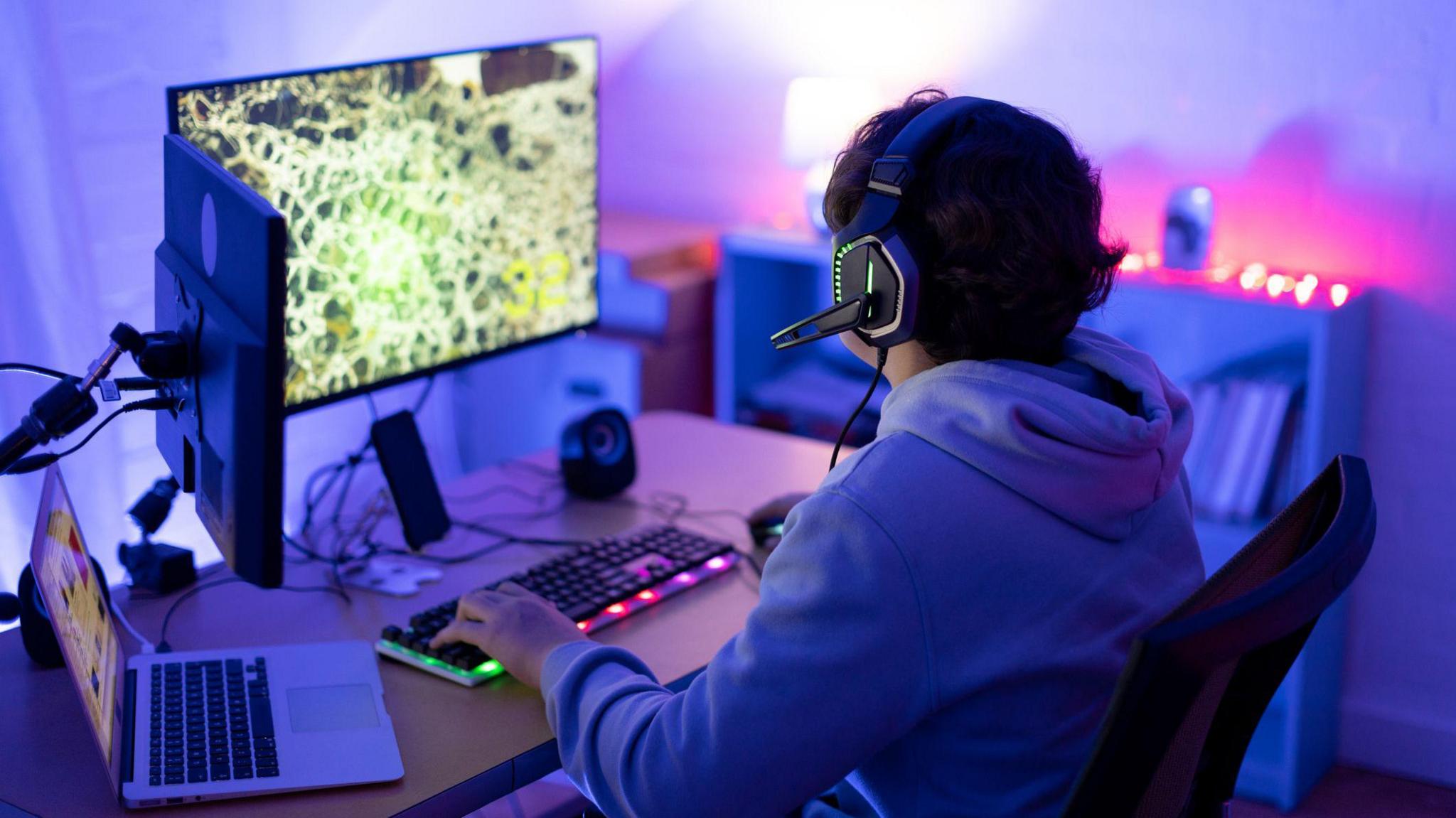 a teenage boy playing a computer game wearing headphones