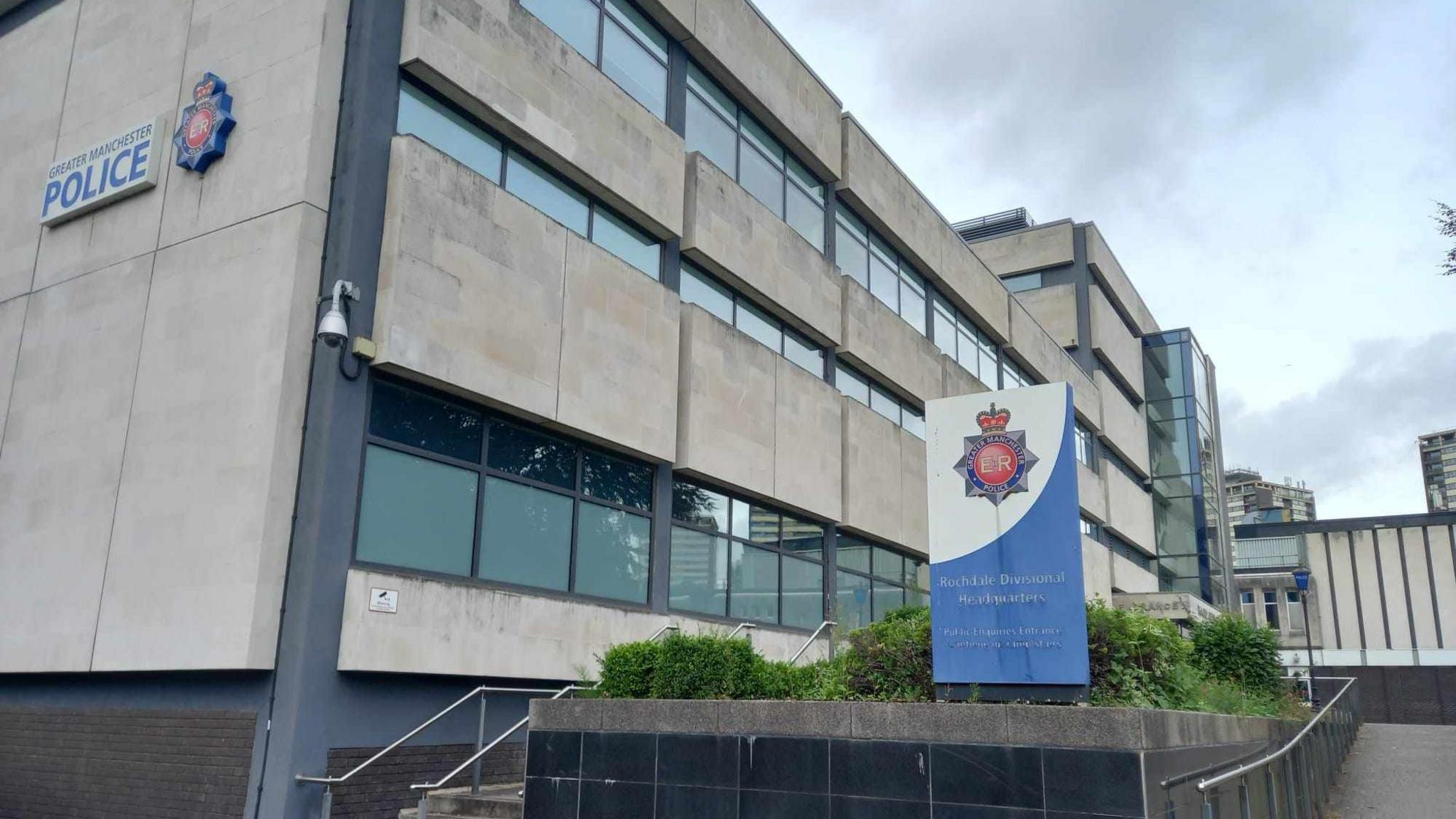 Outside view of Rochdale police station. A blue sign with a police badge says Rochdale Divisional Headquarters. 