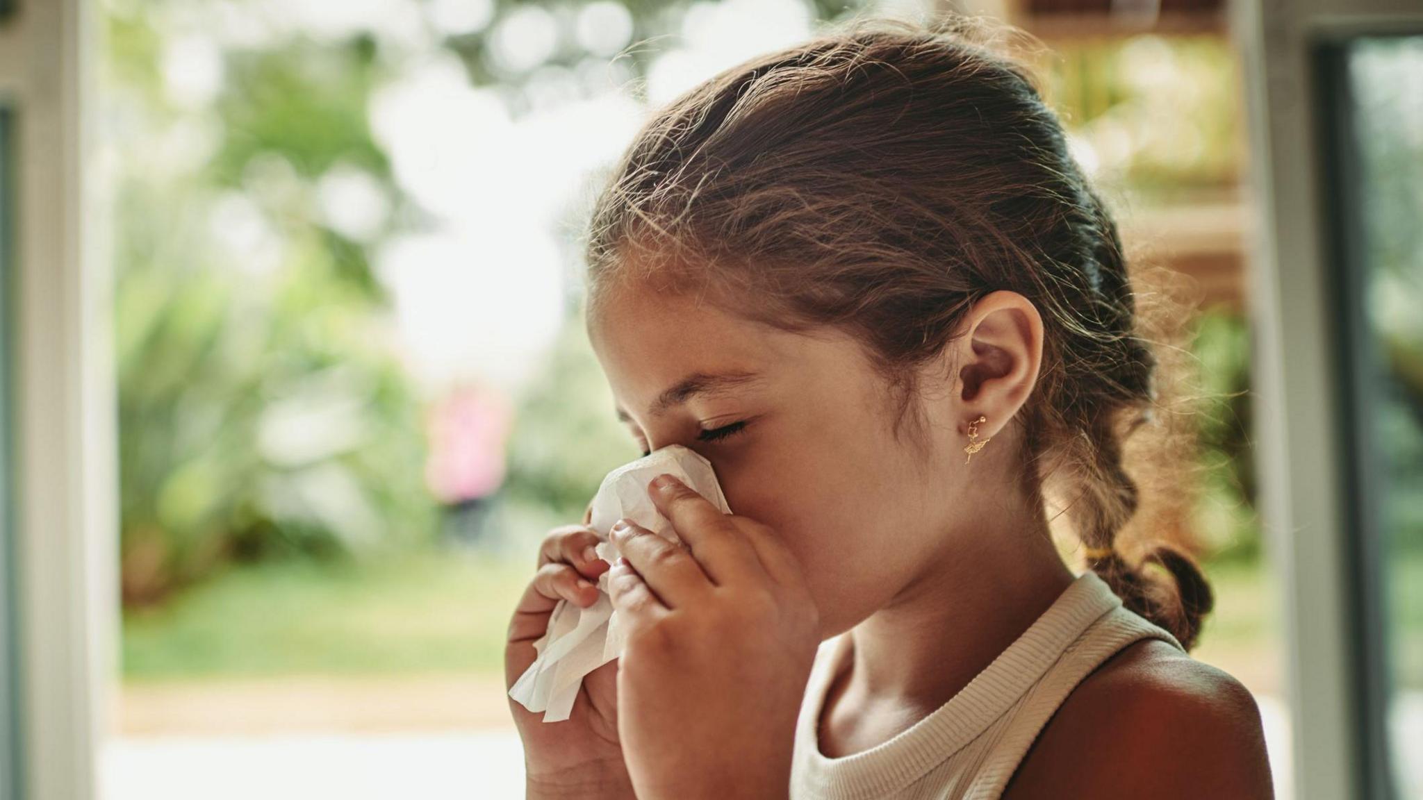 Girl sneezing into tissue