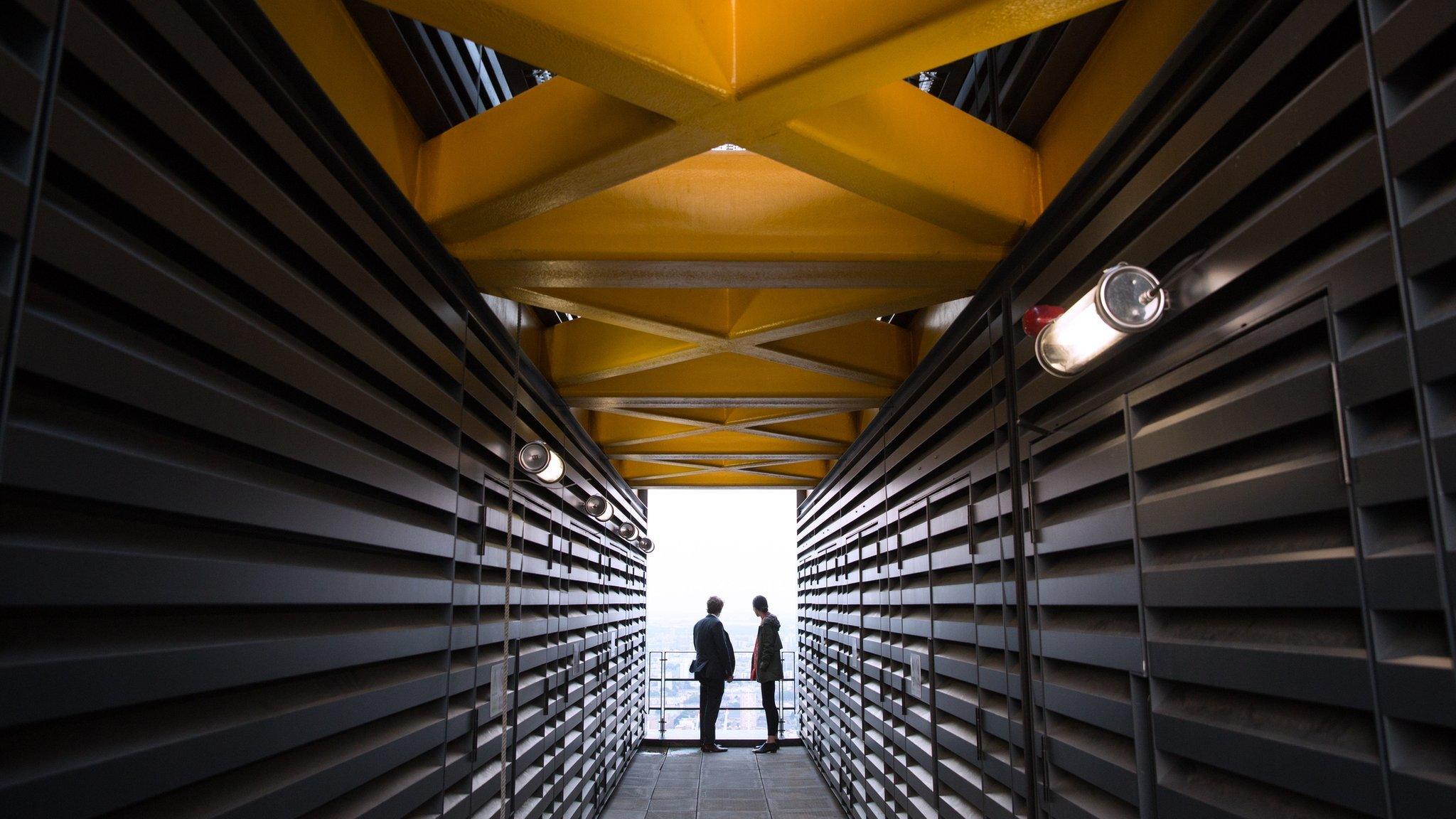 A couple look out at the London skyline from an upper floor of a newly constructed skyscraper, the Leadenhall Building