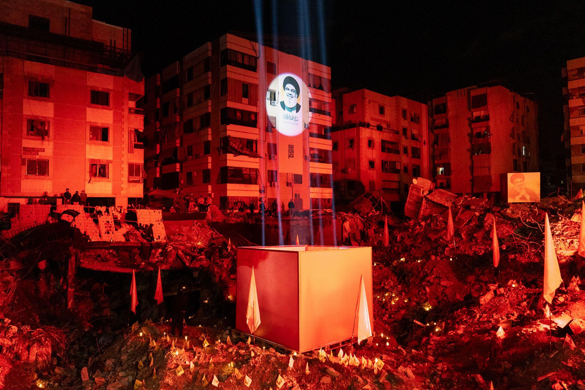 The crater left behind by the Israeli air strike that killed Hassan Nasrallah was lit up in red for the event.