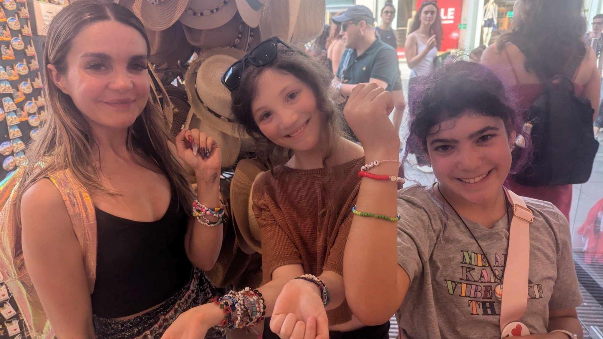 Three girls standing in shop showing friendship bracelets 