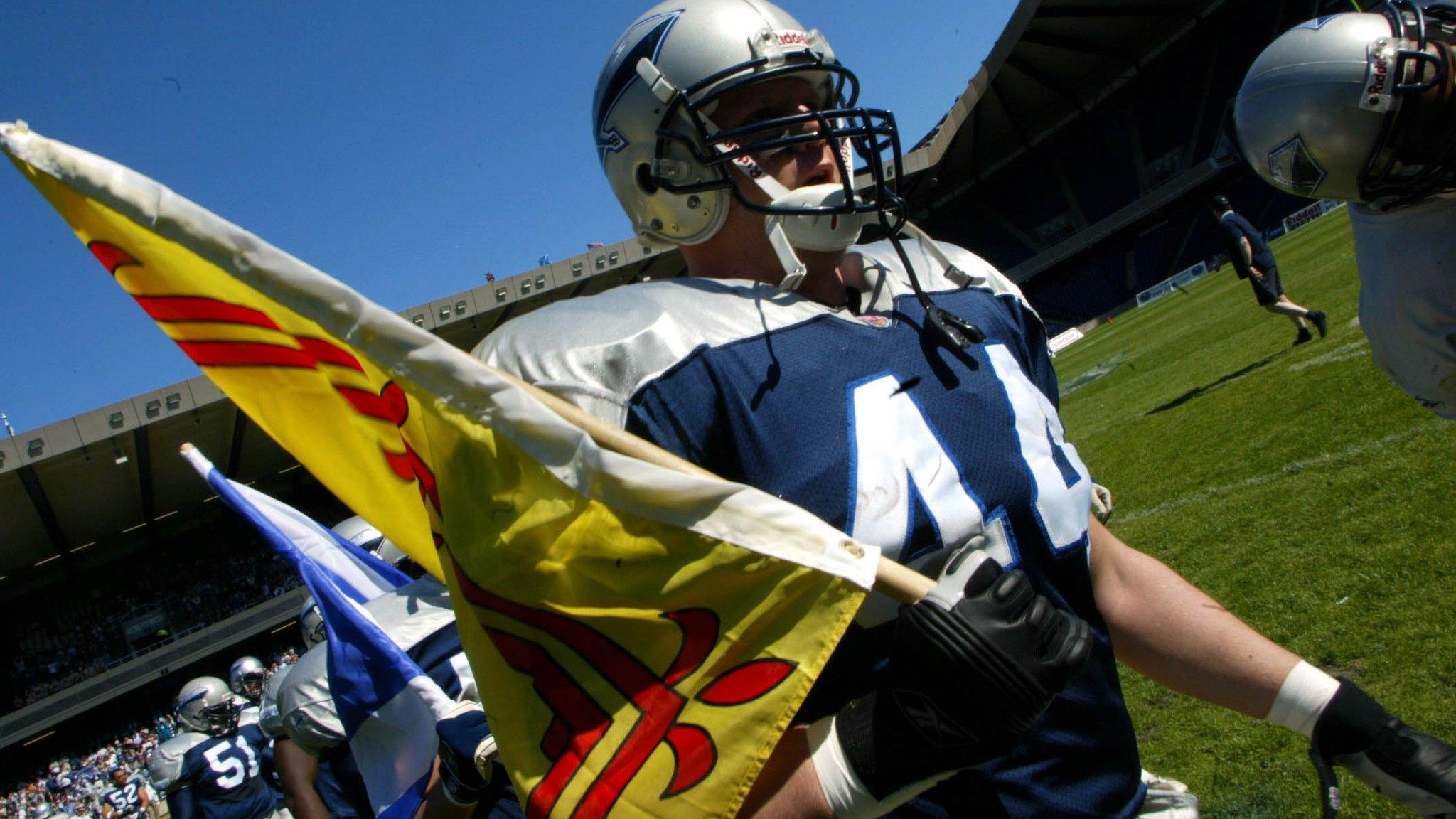 Former Scottish Claymores running back Peter Sochart holds a Scottish flag as he runs out at Murrayfield in 2002