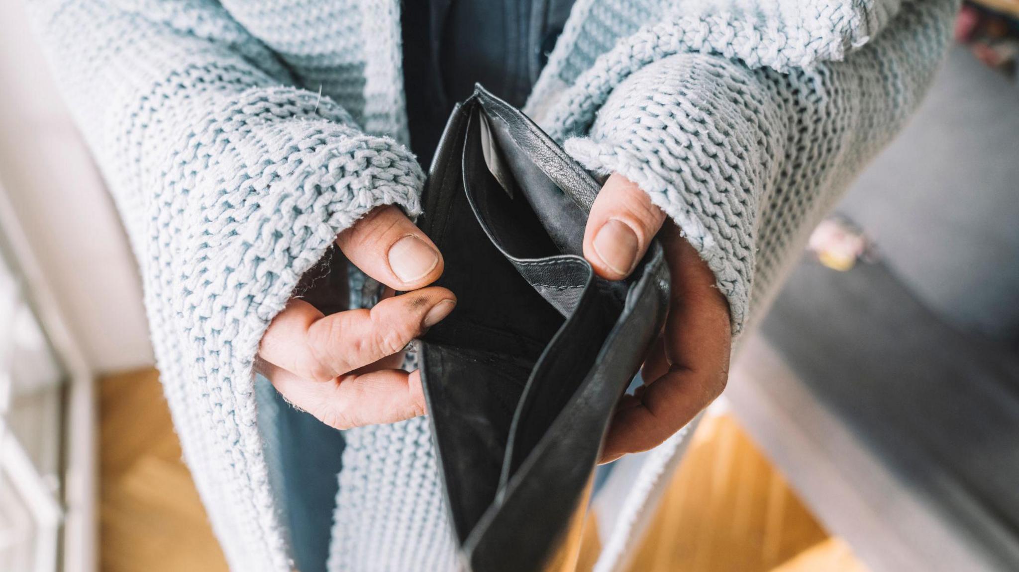 Hands of man wrapped in blanket holding empty wallet