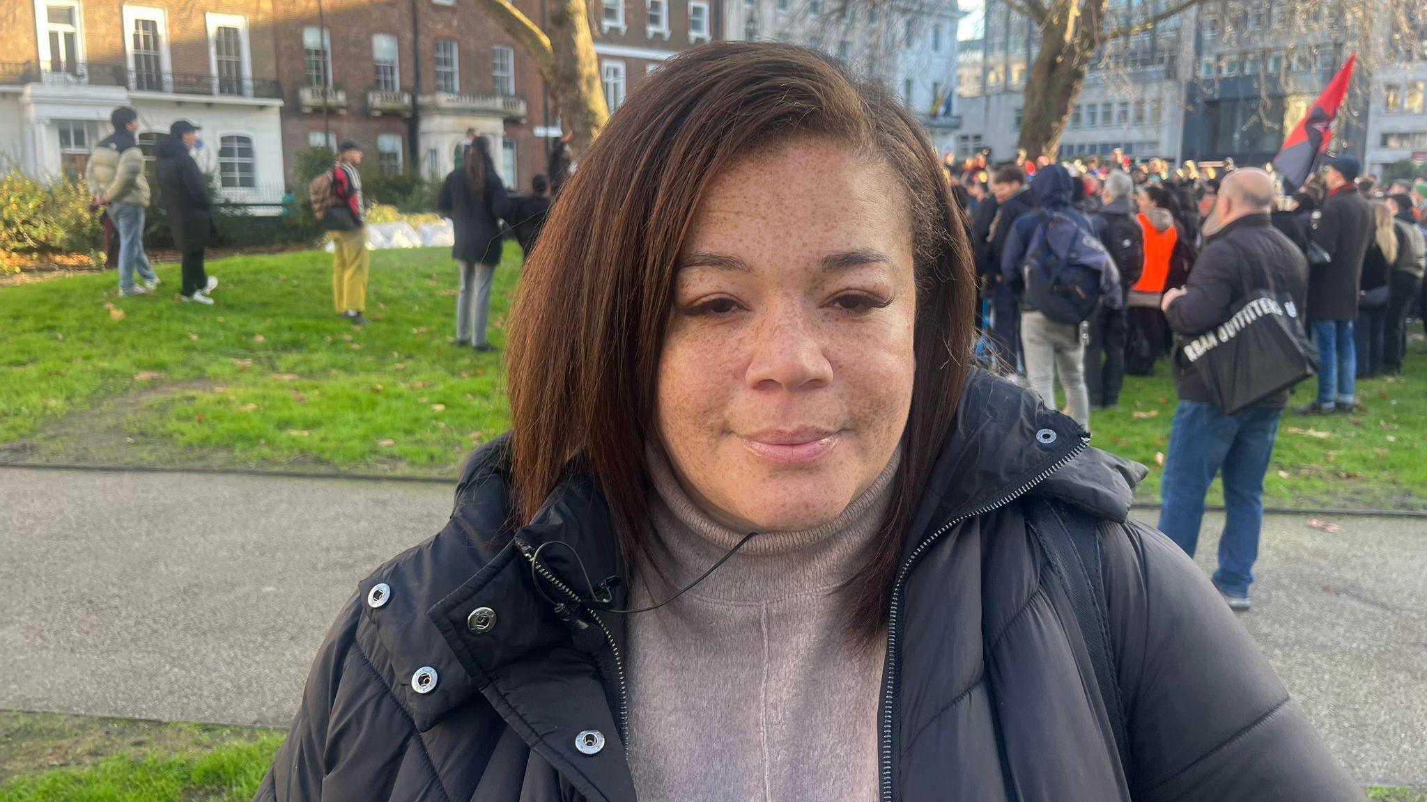 Iola Isaac is seen in front of the other demonstrators in a park.