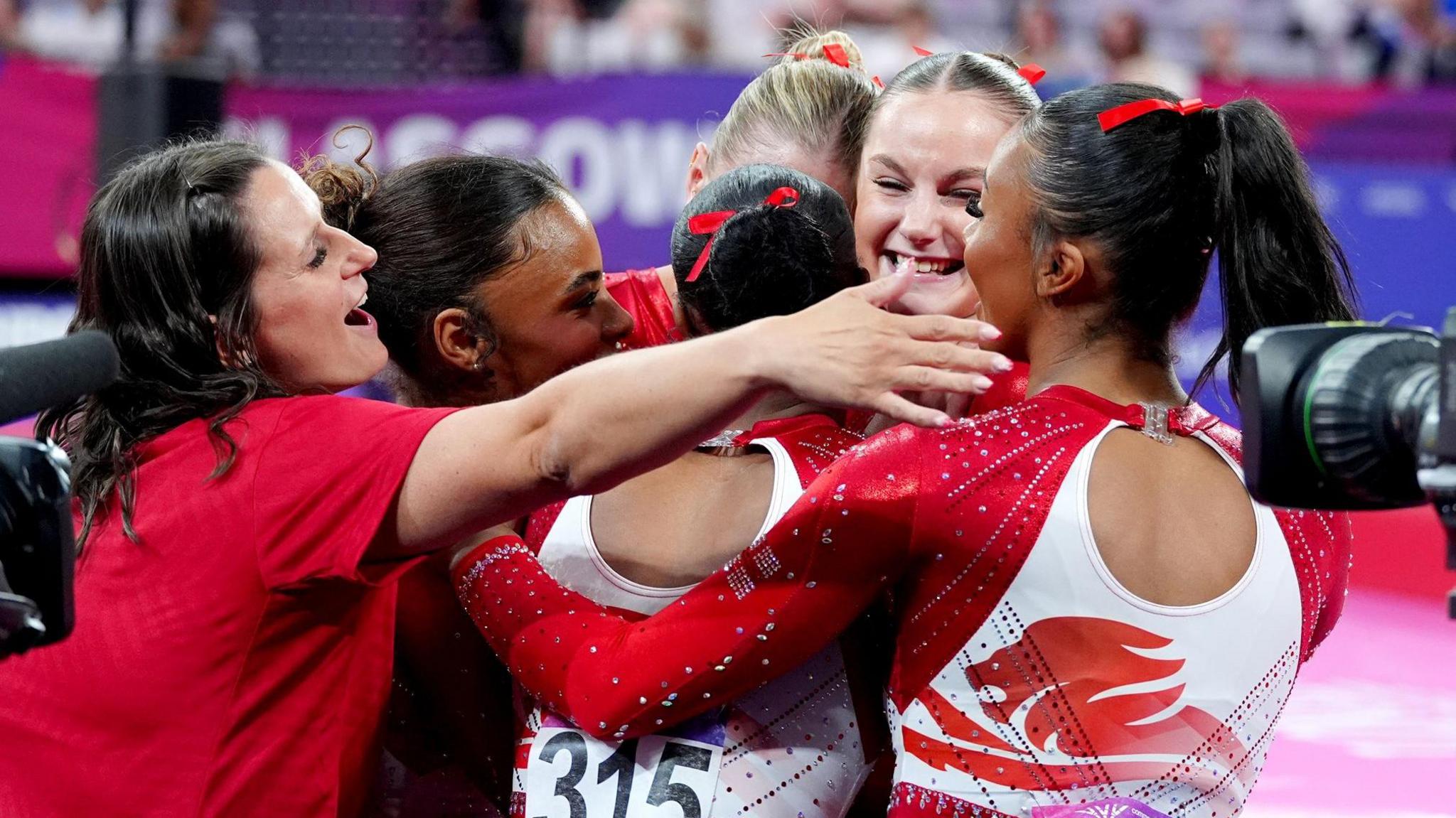 Abi Martin is embraced by her England team-mates after her floor routine secures them bronze at the Commonwealth Games