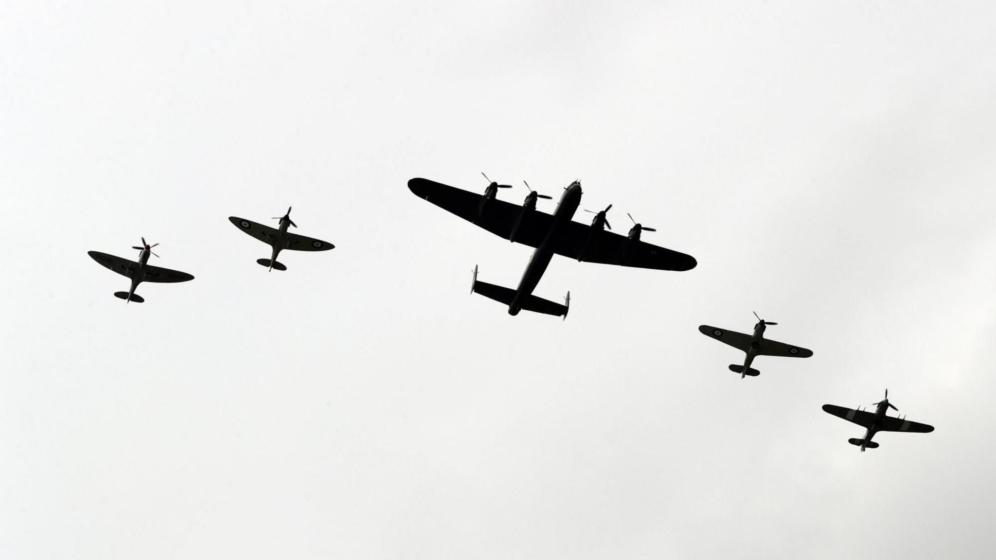 The Battle of Britain memorial flight in the sky - five planes are flying in total, with a larger one in the centre of the formation.