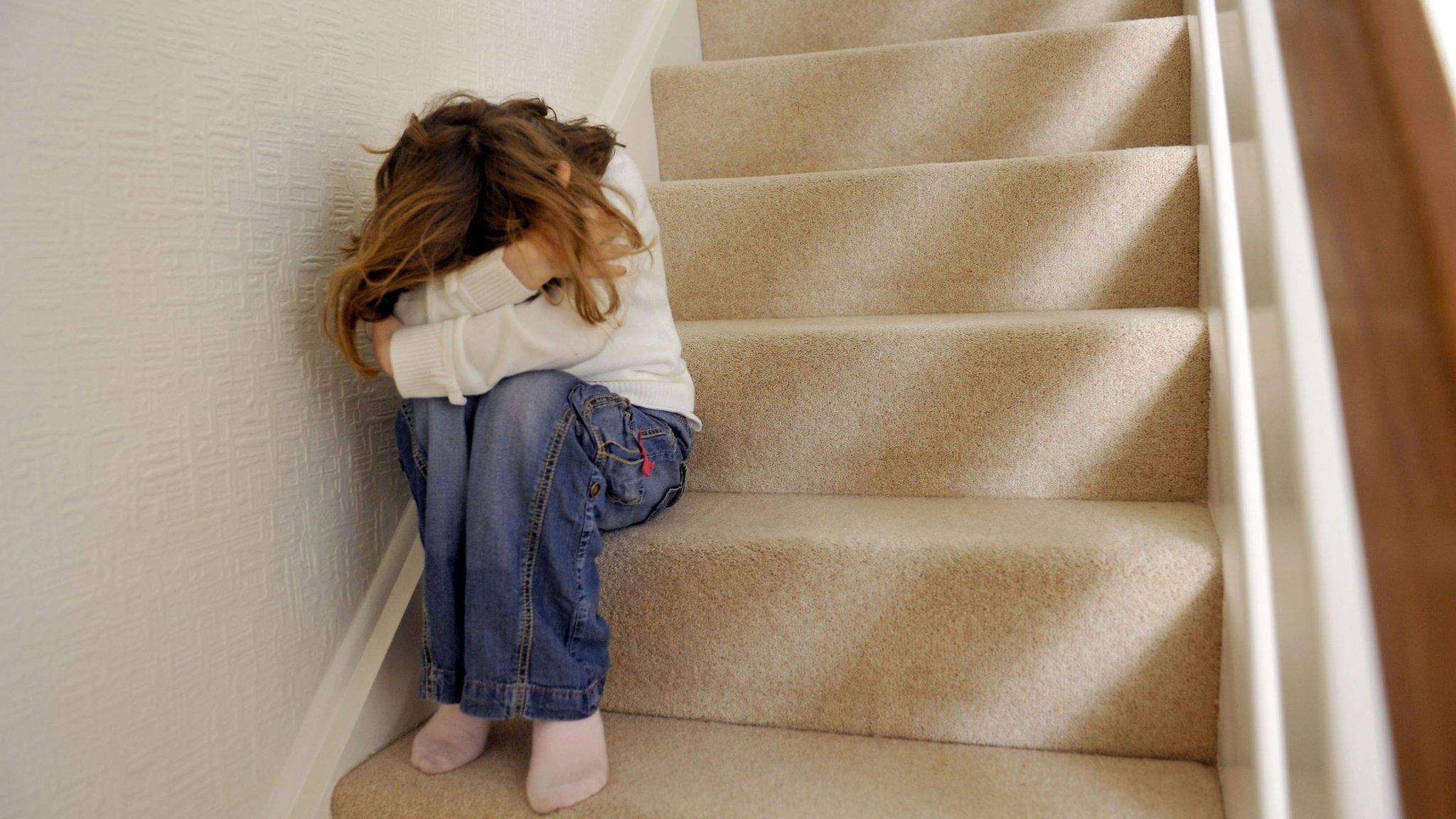 Young girl sitting on stairs with her head in her hands