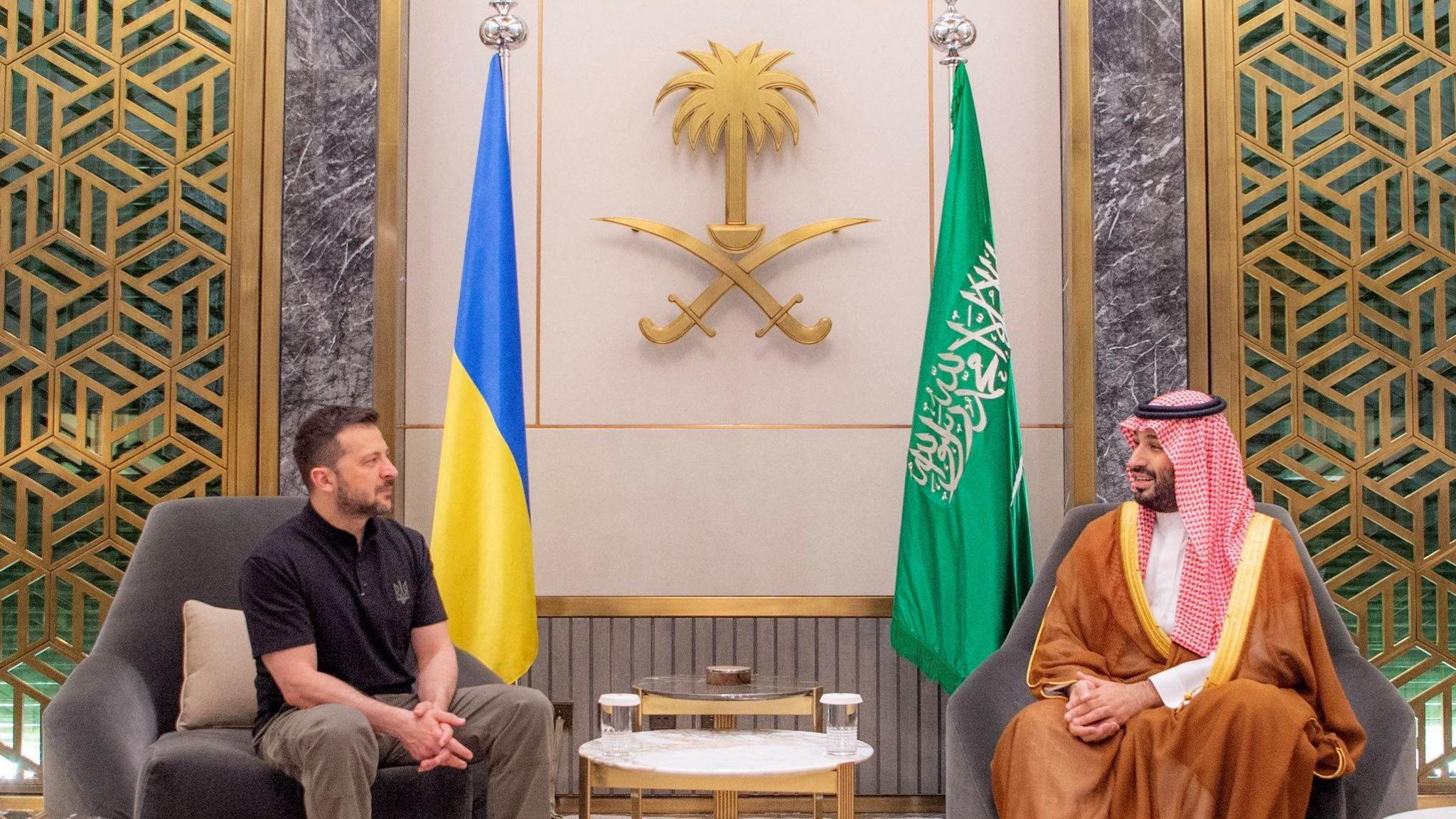 Ukranian President Volodymyr Zelensky and Saudi Crown Prince Mohammed Bin Salman sit on chairs across from one another 