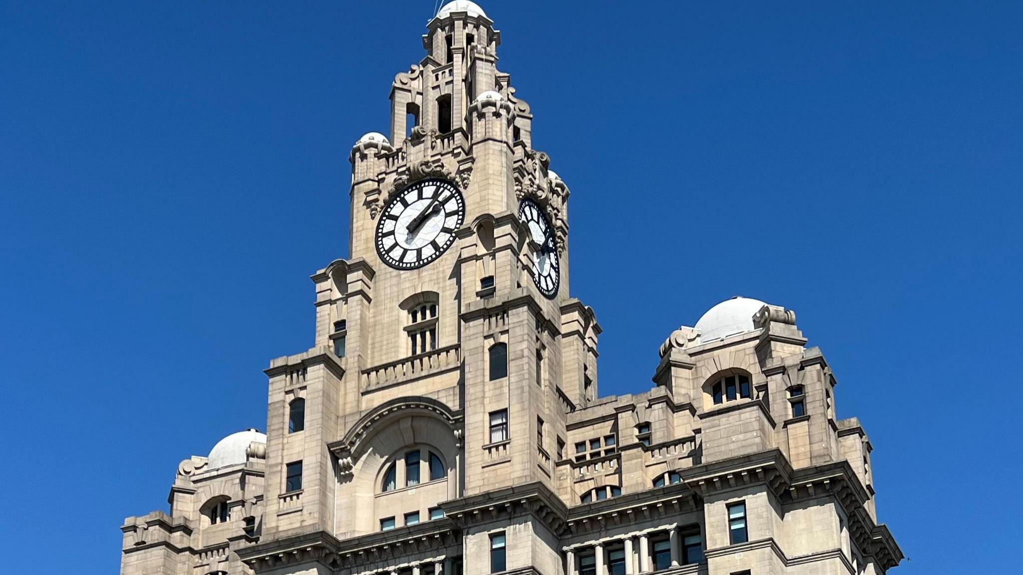 Close up of the clock of Liverpool's Royal Liver Building against a blue sky