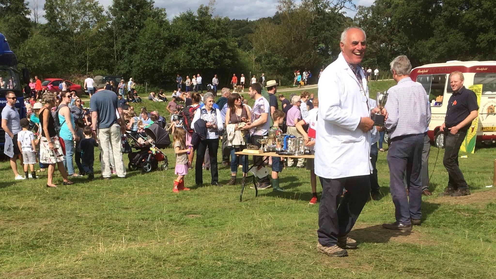 Crowds mingling at Ripley Show. Groups of people chat in a field, with an ice cream van and food stall seen in the corner.