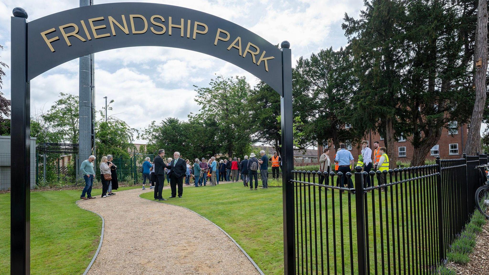 The opening of the park site with dignitaries and members of the public on the new park behind an archway entrance and fencing