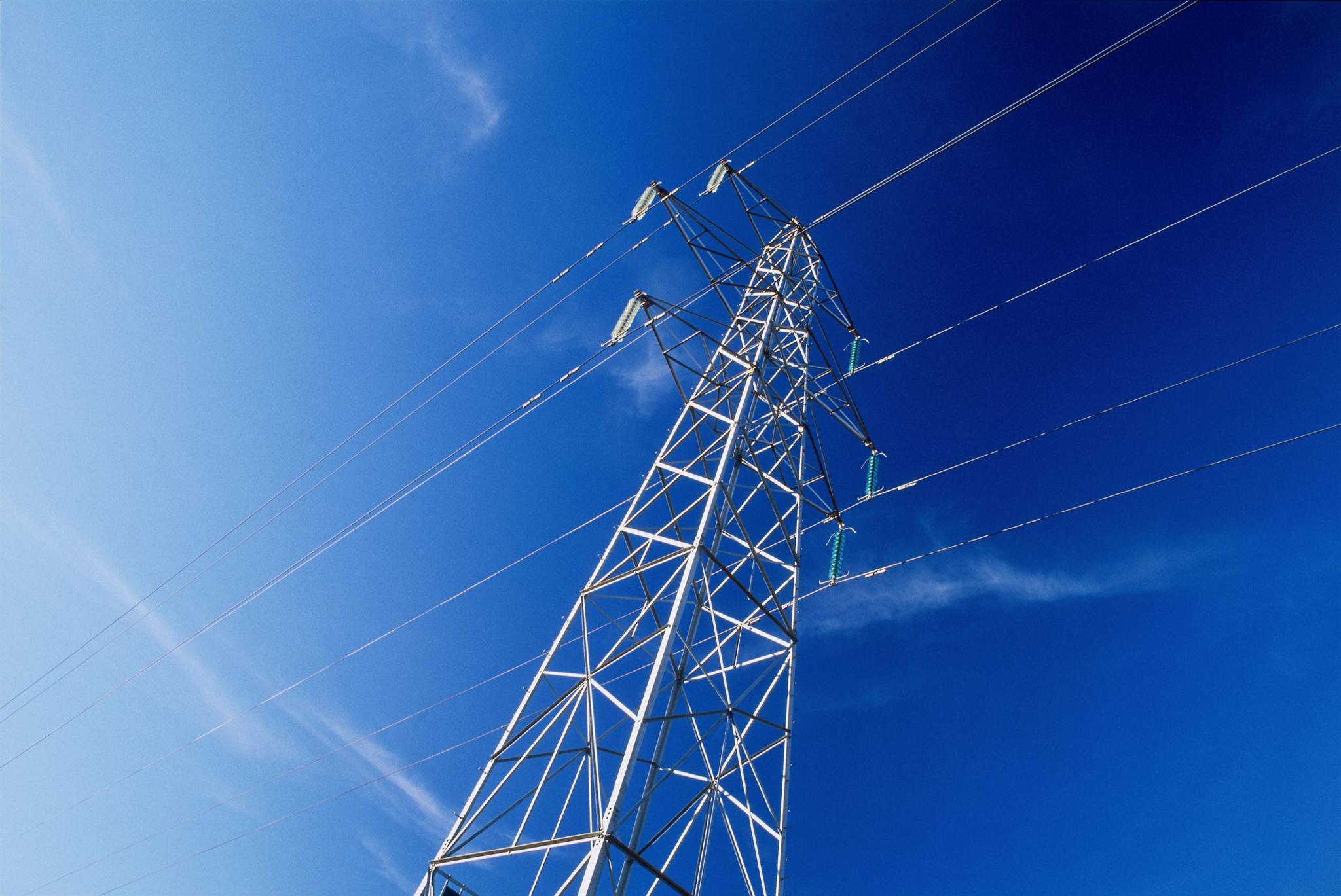 A large electricity pylon with cables against a blue sky