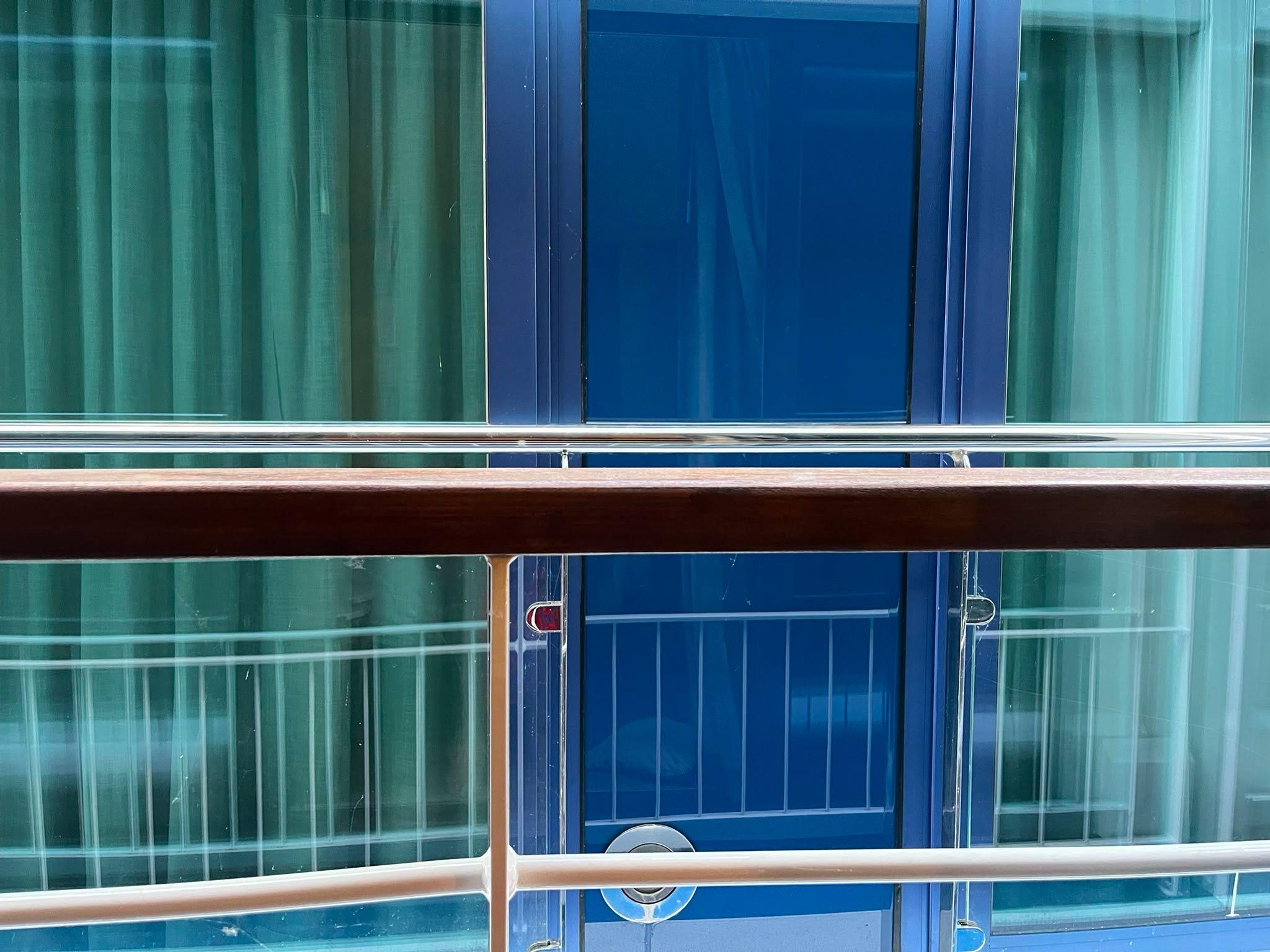 A photo taken from a cruise ship balcony, showing a very close up view of another vessel docked alongside it.