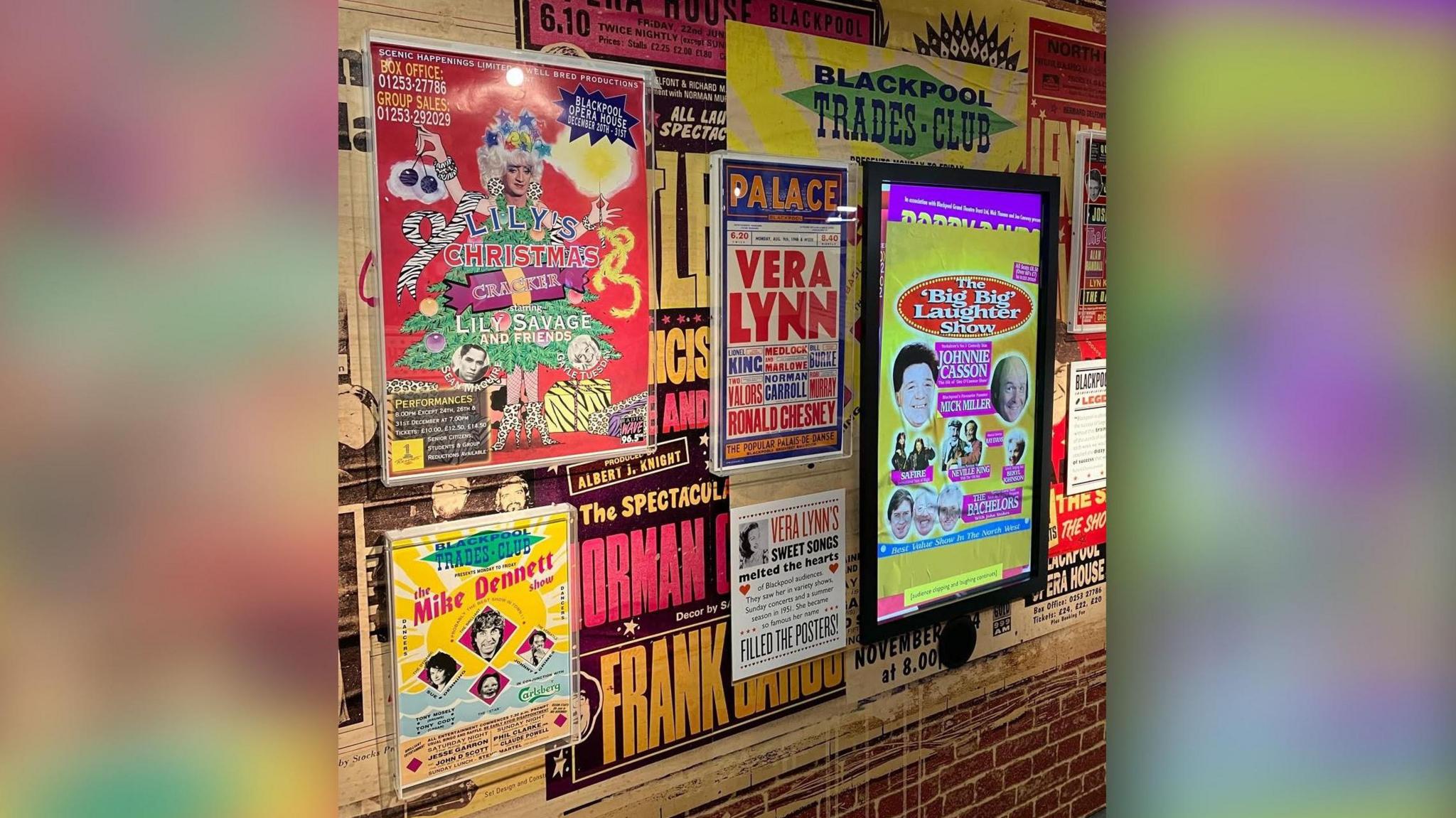 A poster advertising The Mike Dennett Show at Blackpool Trades Club can be seen on a wall of show posters at the Showtown museum. Mike Dennett's face is featured alongside three other performers. The poster includes a sun design with waves and sand beneath.