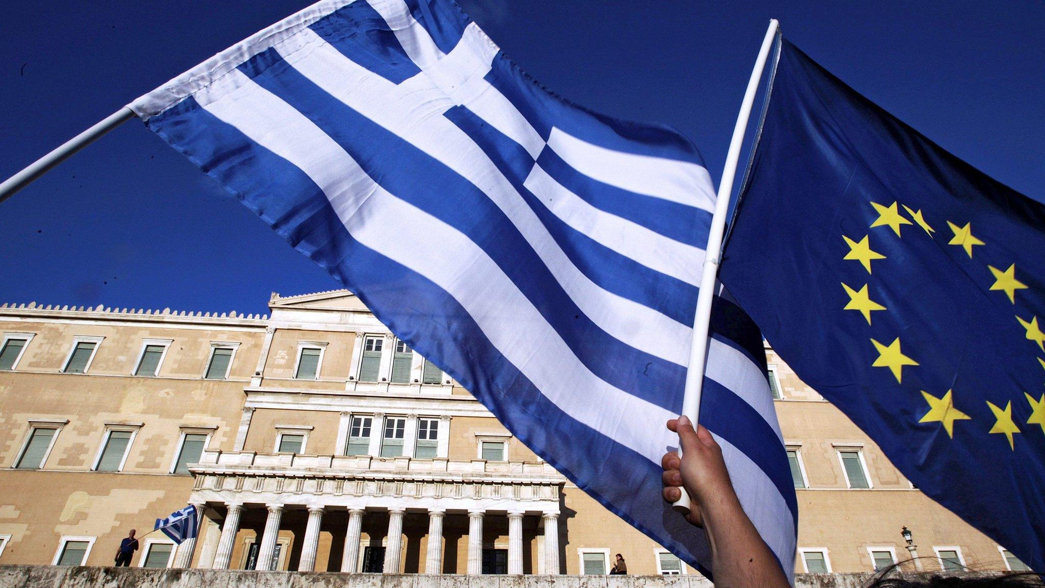 Protesters hold a Greek and a EU flag outside the parliament during a rally in Athens on 22 June 2015.