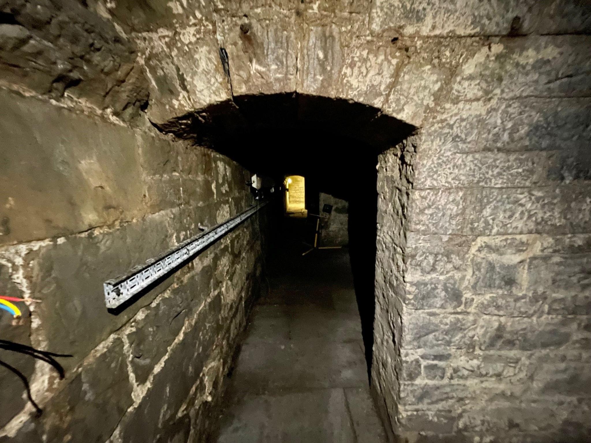 A stone arch leading into a dark room.