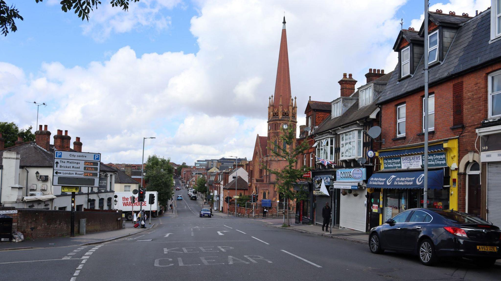 Victoria Street. There is a road with shops on either side, and a red brick church on the right.