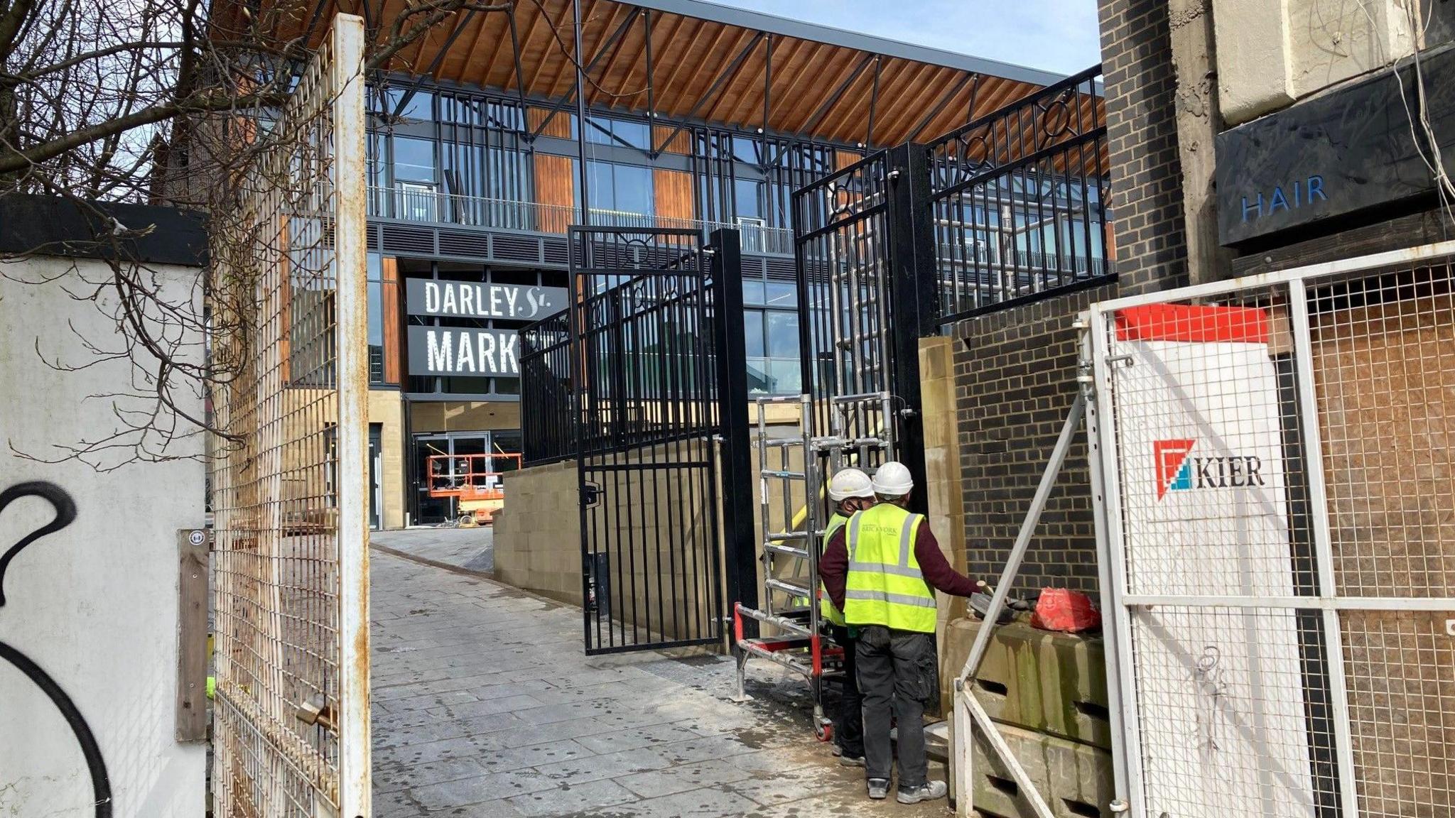 Two construction workers working near the front gates of Darley Street Market in Bradford 