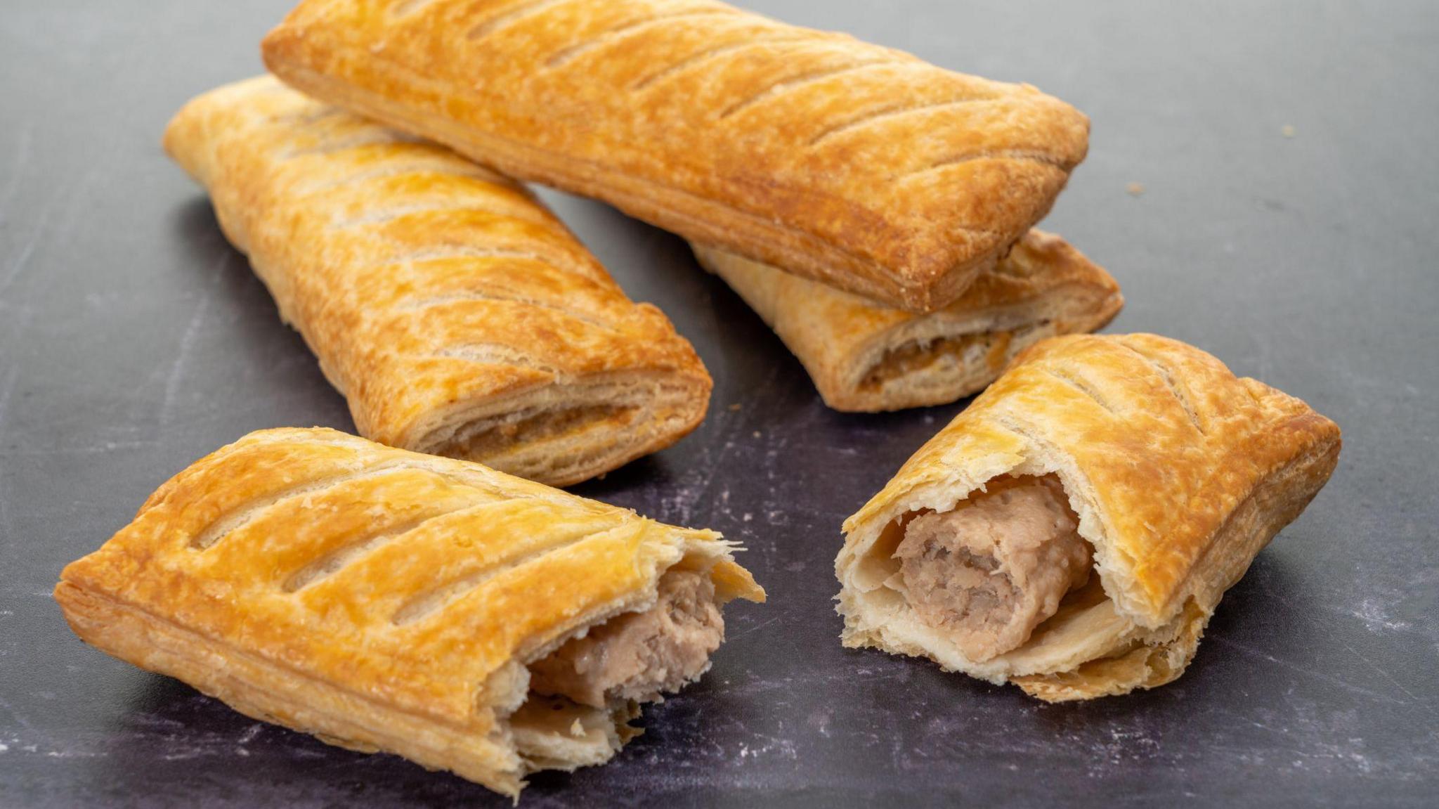 Stock image of sausage rolls laid out on a surface.
