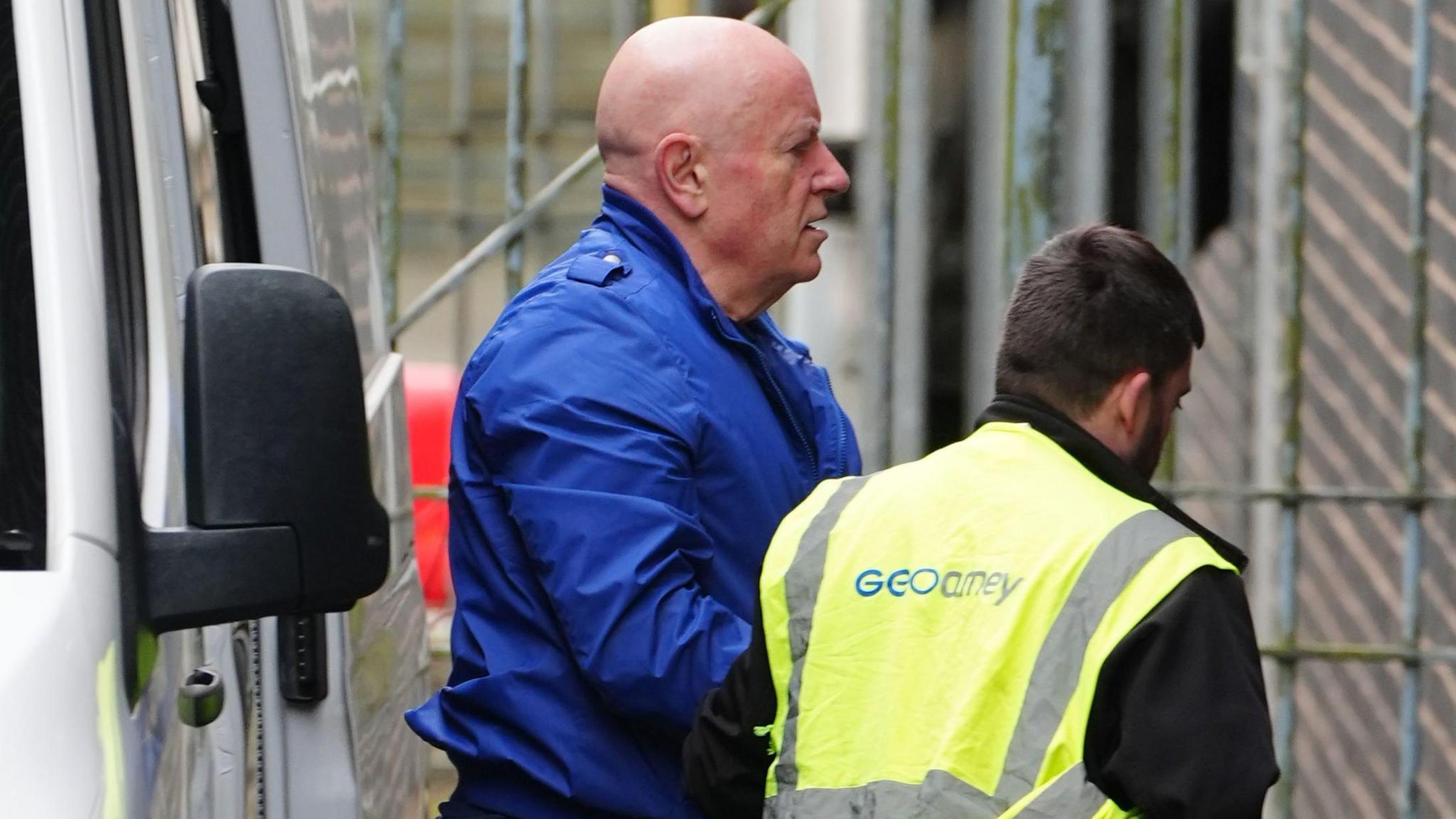 Neil foden being led from a prison van into court