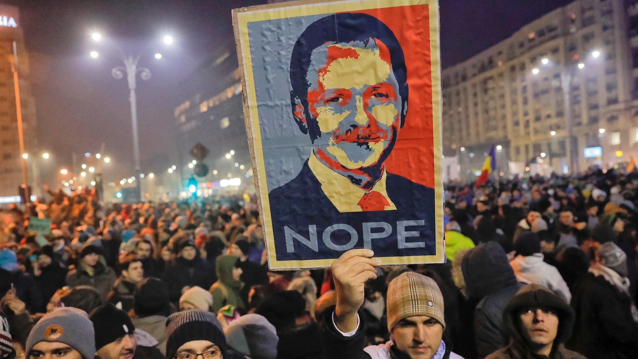 A man holds a poster depicting the leader of the ruling Social Democratic party Liviu Dragnea, during a protest in Bucharest, Romania, early on Wednesday 1 February 2017 after the government adopted an emergency ordinance late Tuesday to decriminalise official misconduct