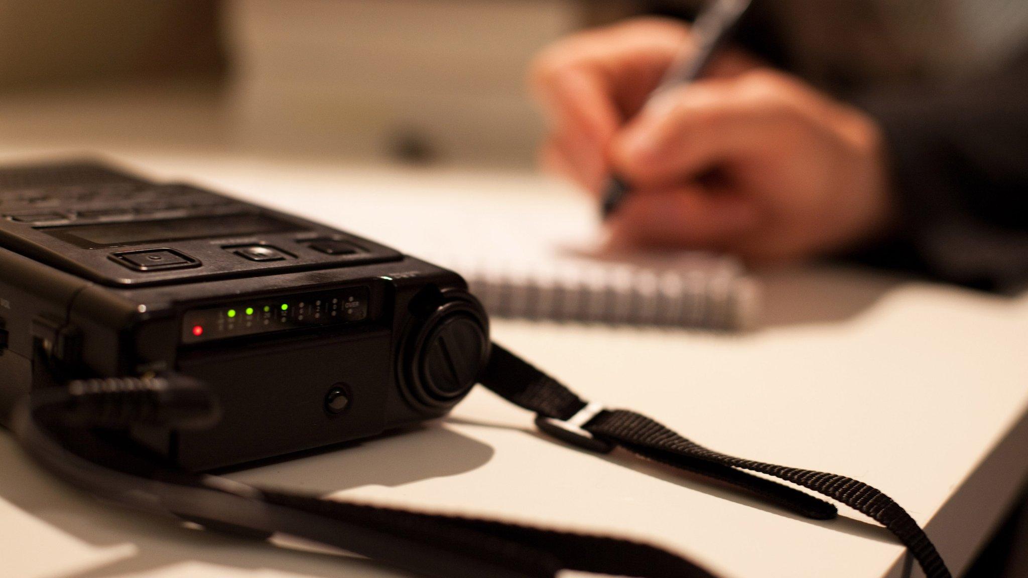 Person using a dictaphone and notepad