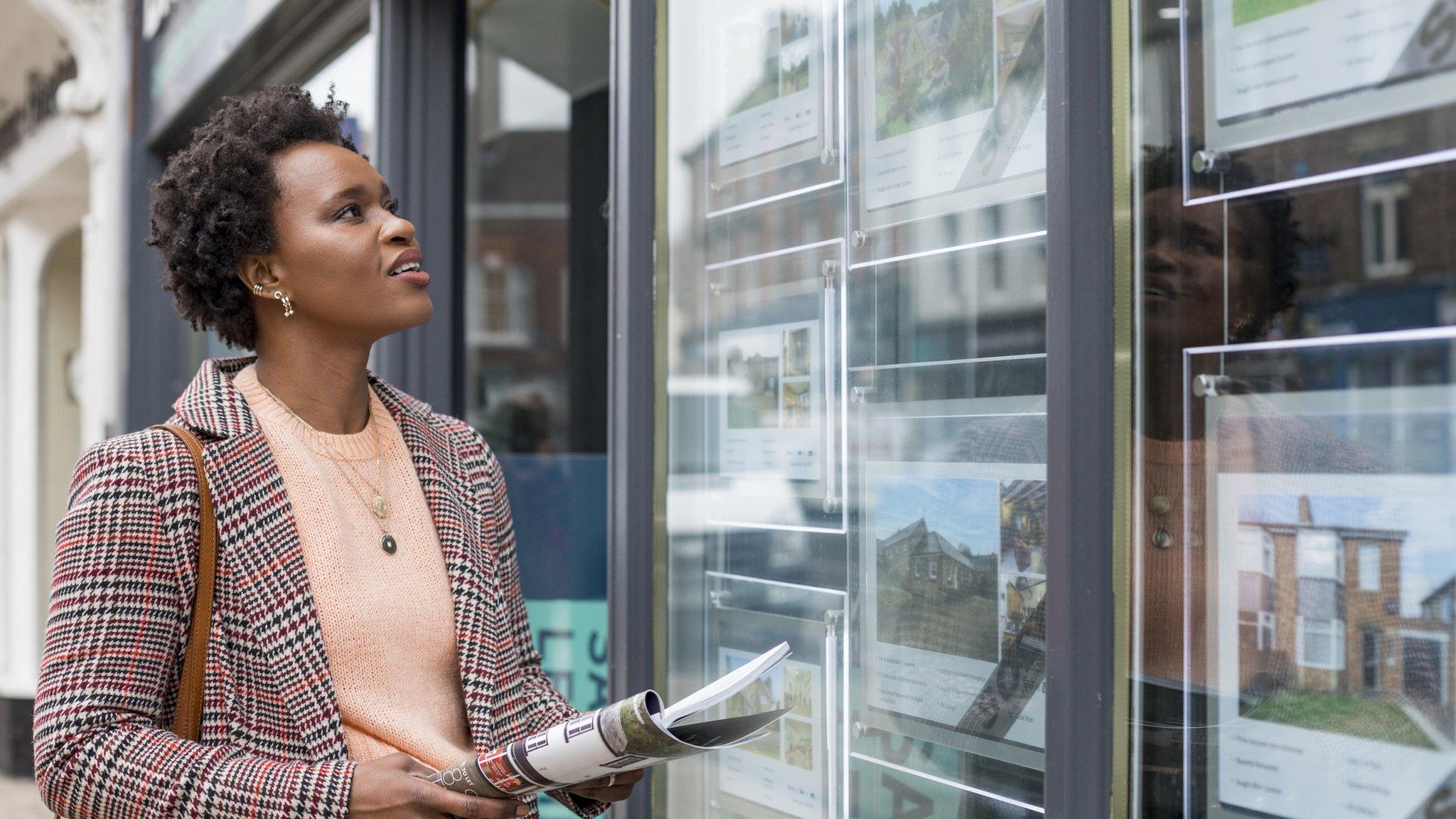 Woman looking in estate agent window