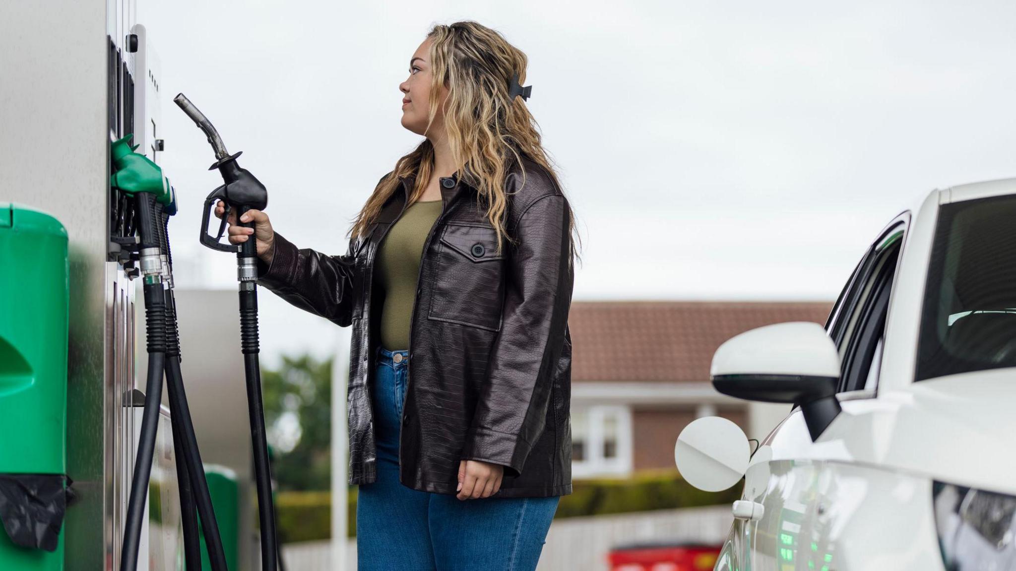 Woman filling a car at a petrol station - stock shot