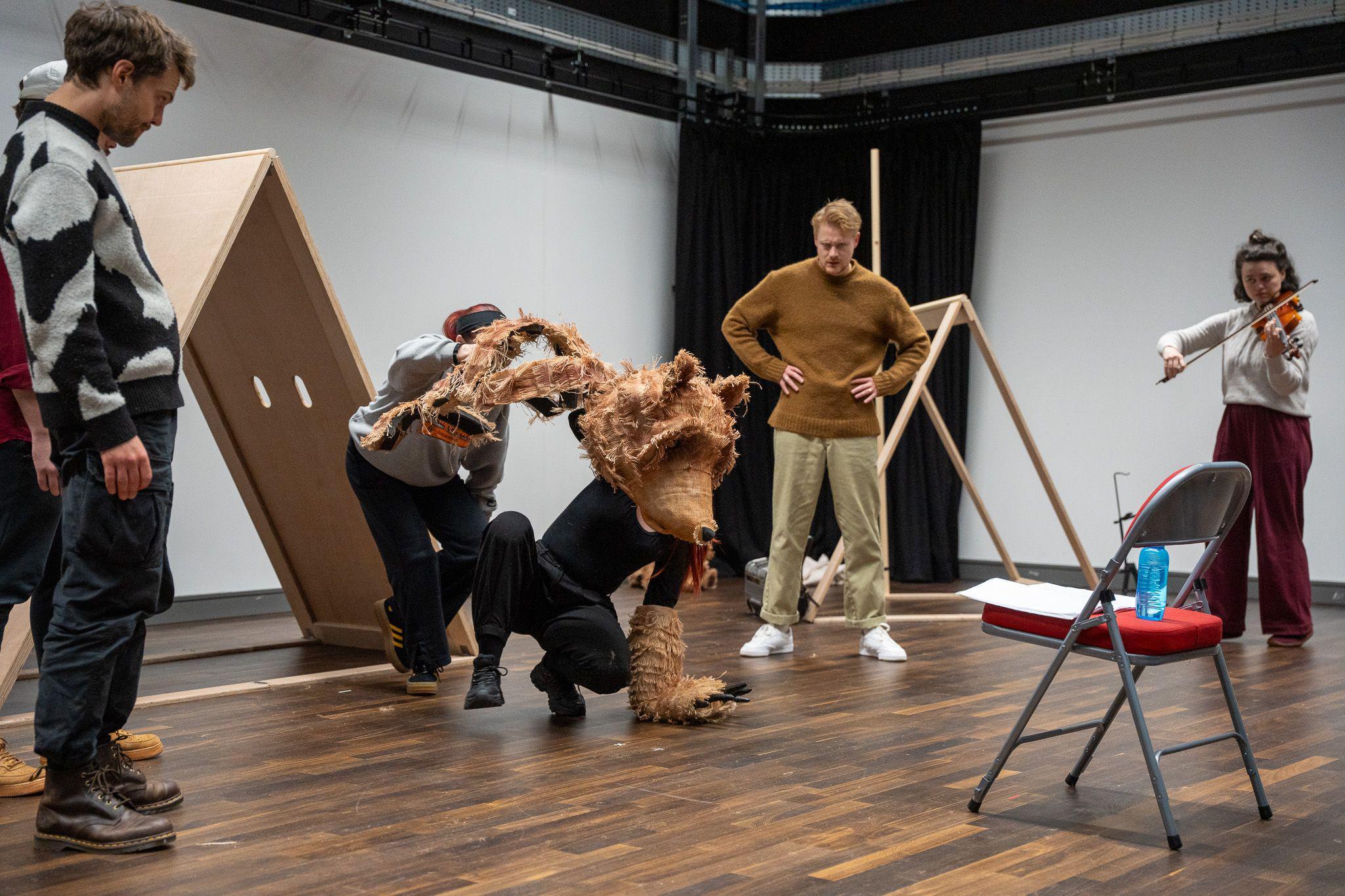 Actors rehearse for a production of The Bear Who Went to War. They can be seen playing a violin with two actors dressed as Wojetek the bear