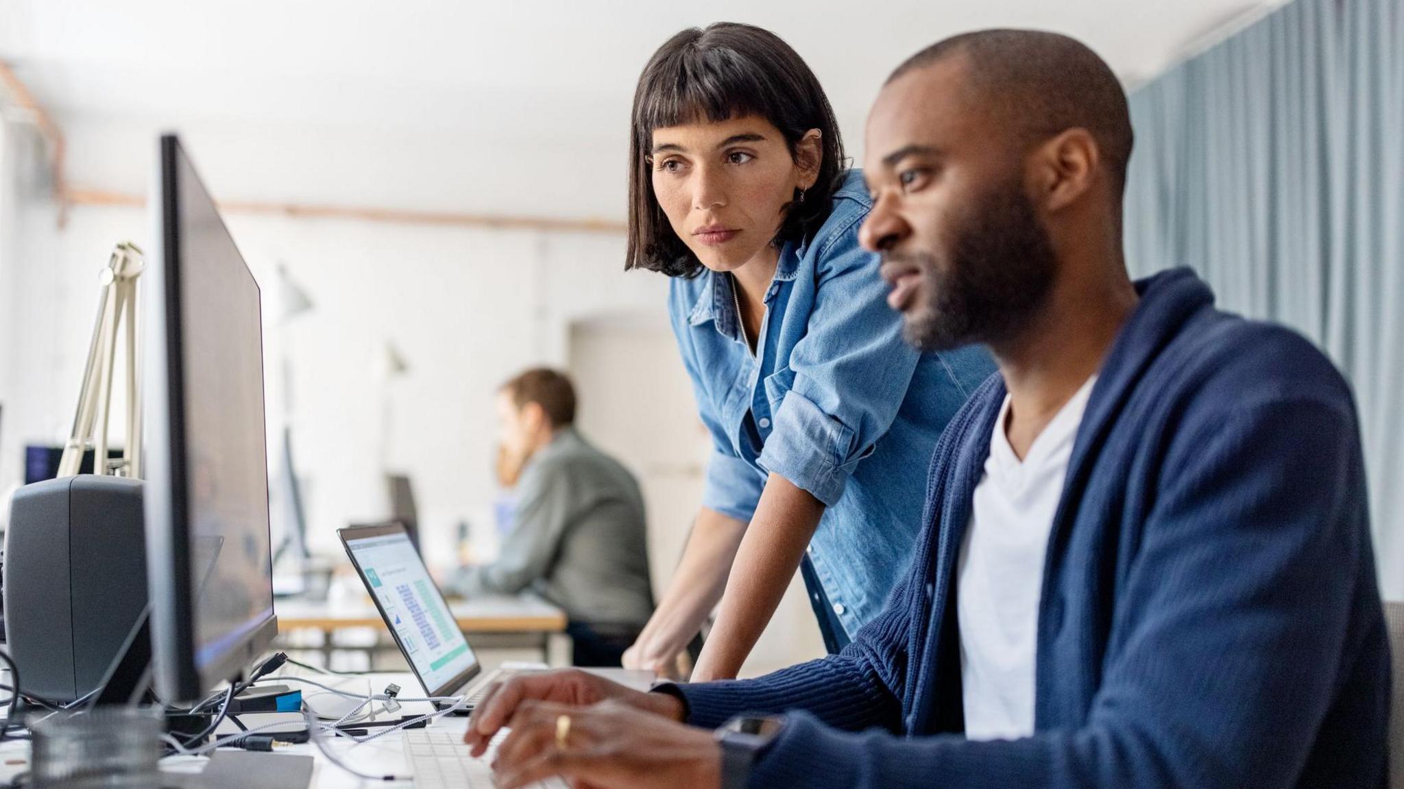 A man and a woman looking at a computer screen in an office
