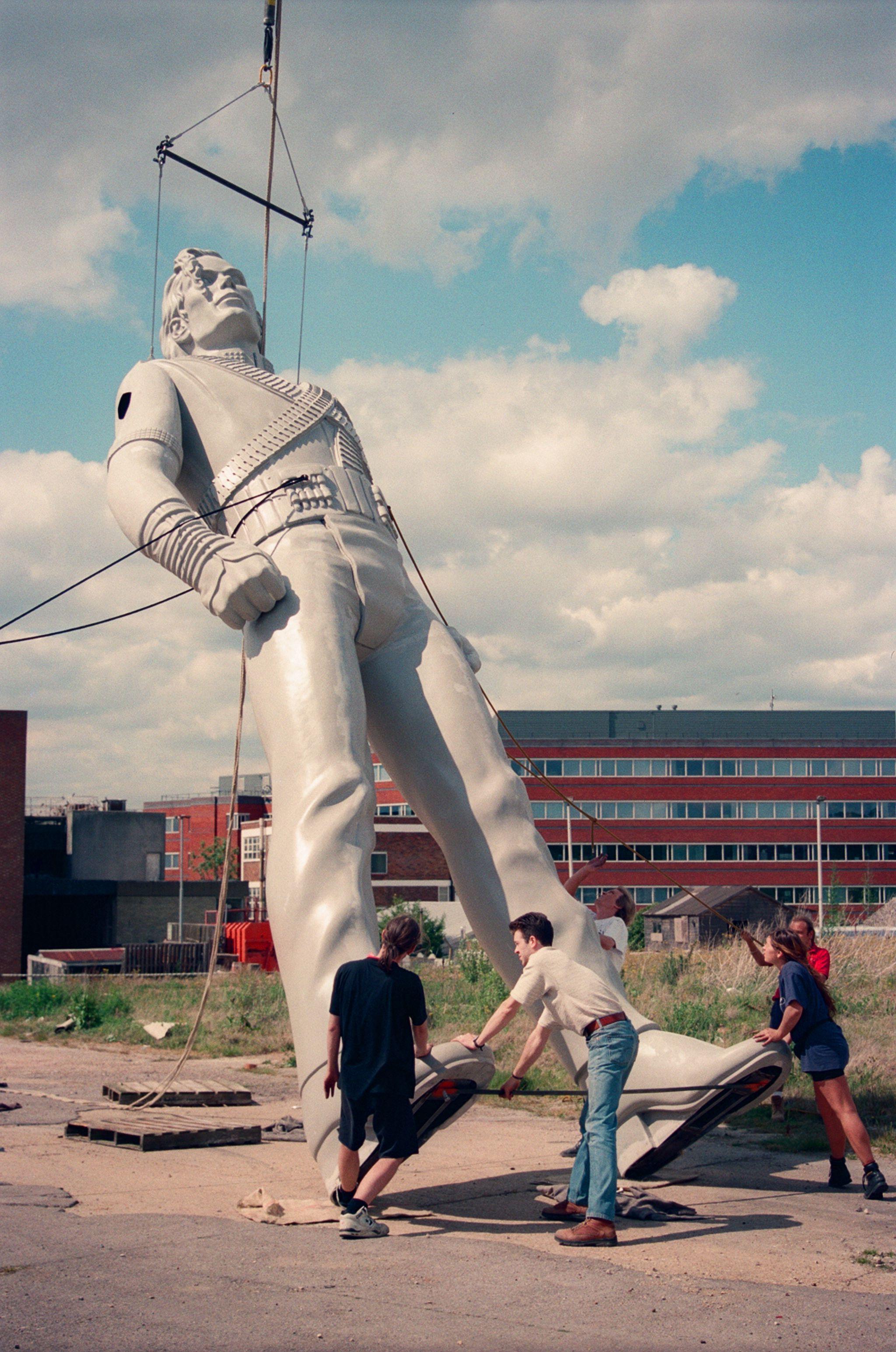An old photo shows a large Michael Jackson statue is being hoisted on to its feet by people pulling on ropes.