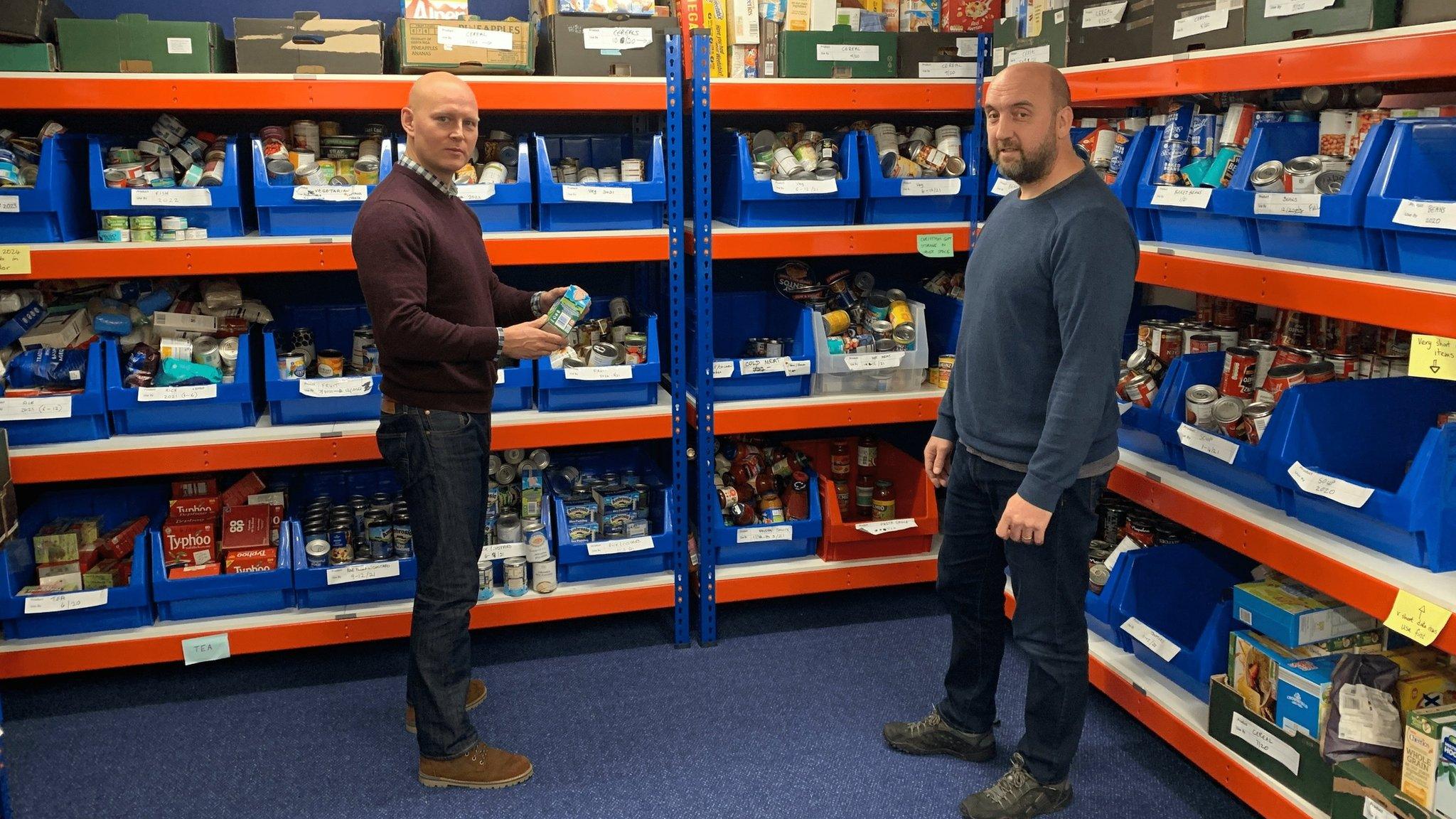 Two men surrounded by groceries at a food pantry